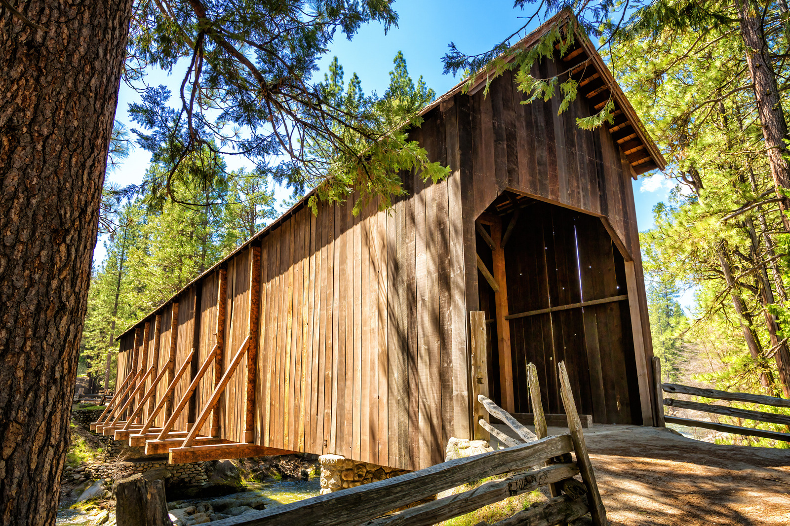 Historic wooden Wawona Swinging Bridge surrounded by pine trees in Yosemite National Park