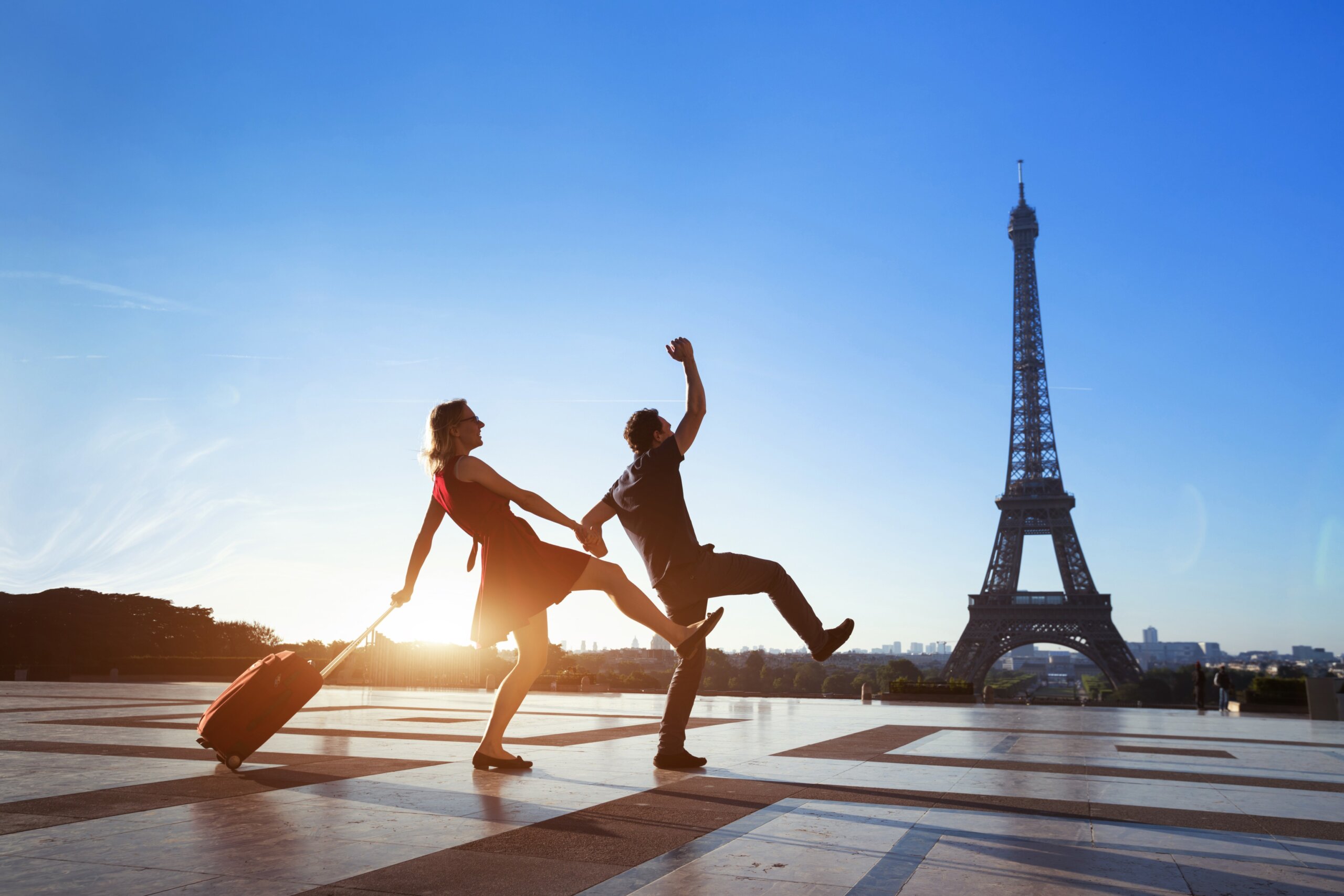 couple of crazy tourists on holidays in Paris, man and woman having fun near Eiffel Tower, travel with luggage, tourism
