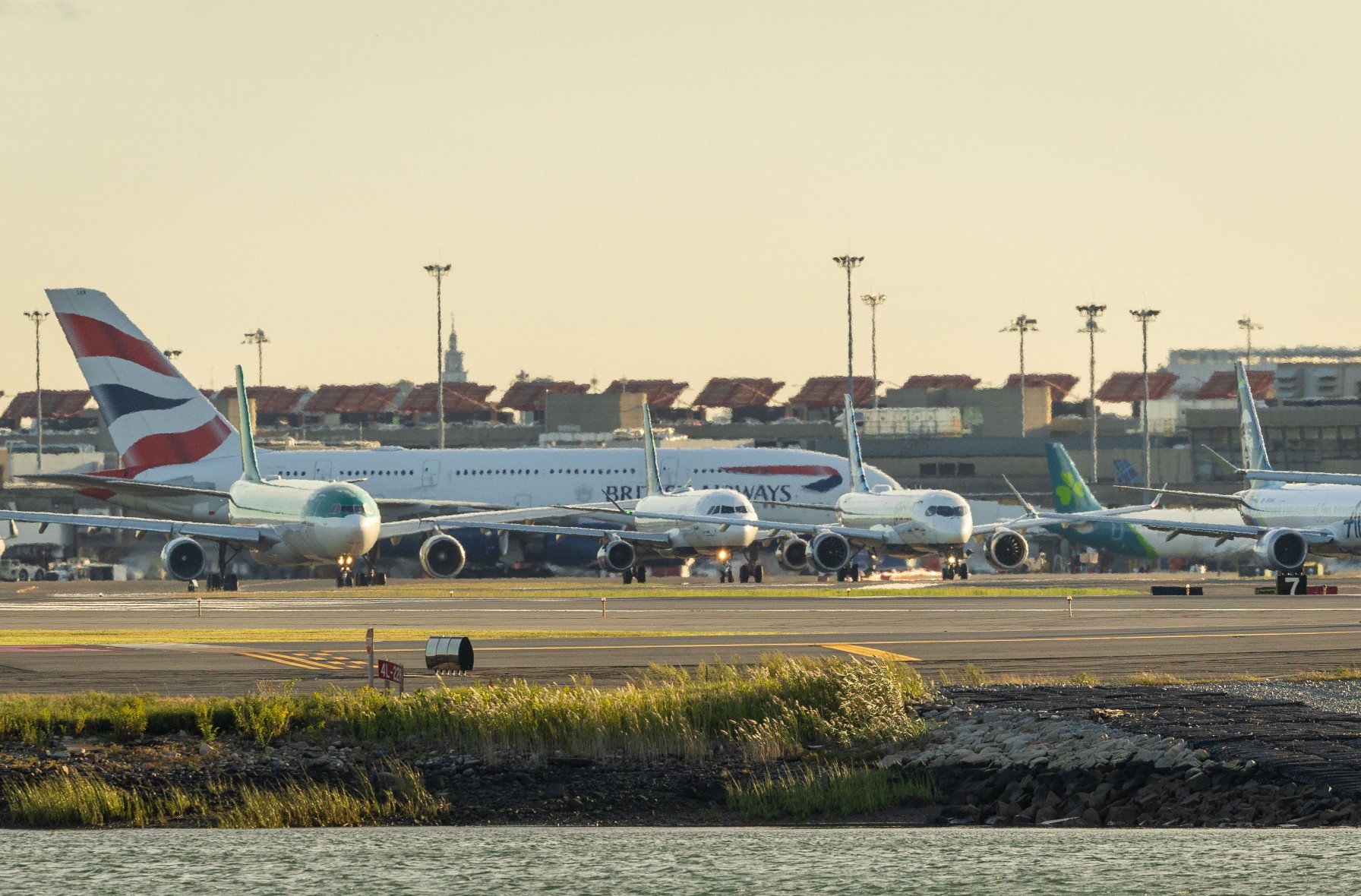 Airplanes lined up on a runway at sunset.
