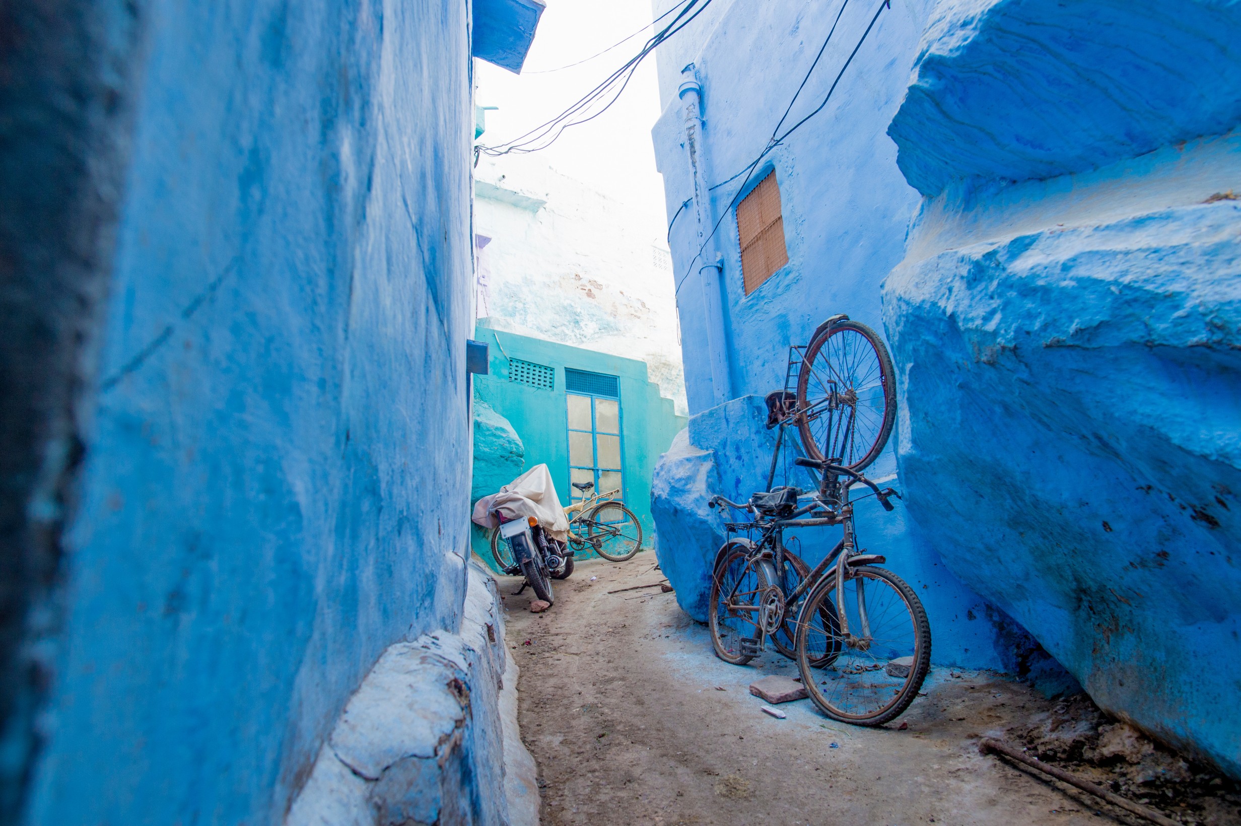 A bike and a motorcycle in a small alleyway in the blue city of Jodhpur, Rajasthan, India.
