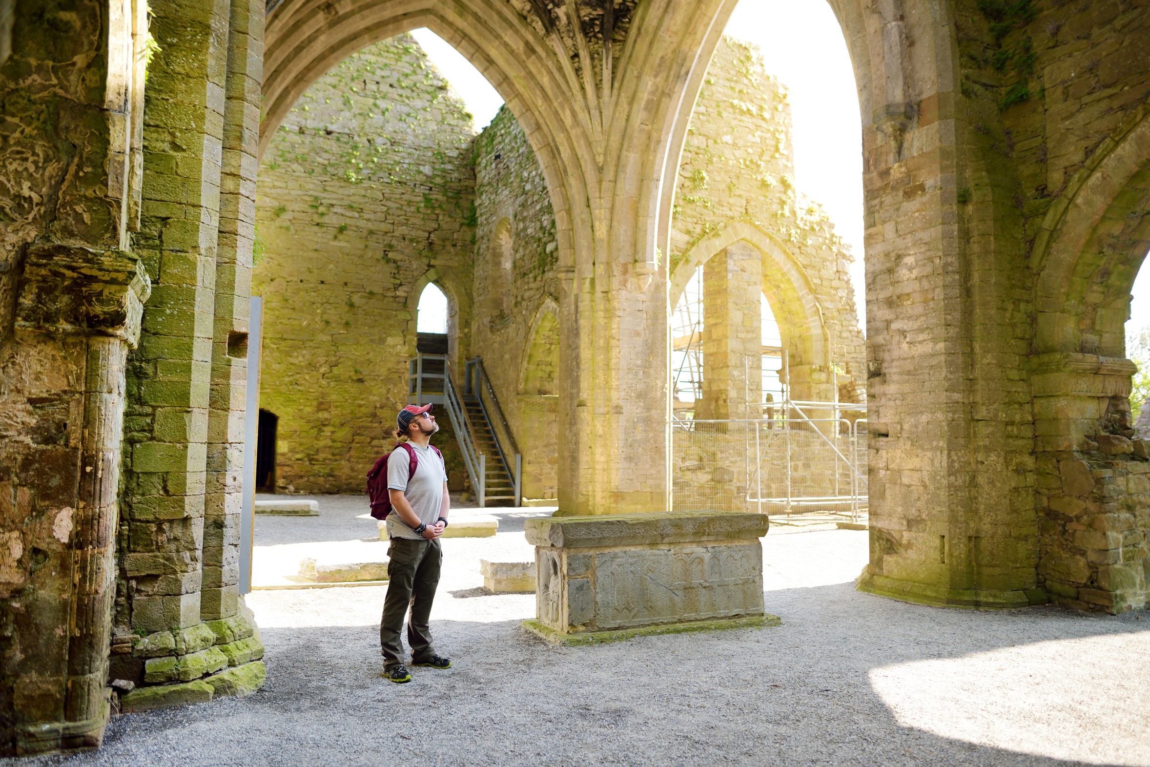 Male tourist in Jerpoint Abbey, a ruined Cistercian abbey, located near Thomastown, County Kilkenny, Ireland.
