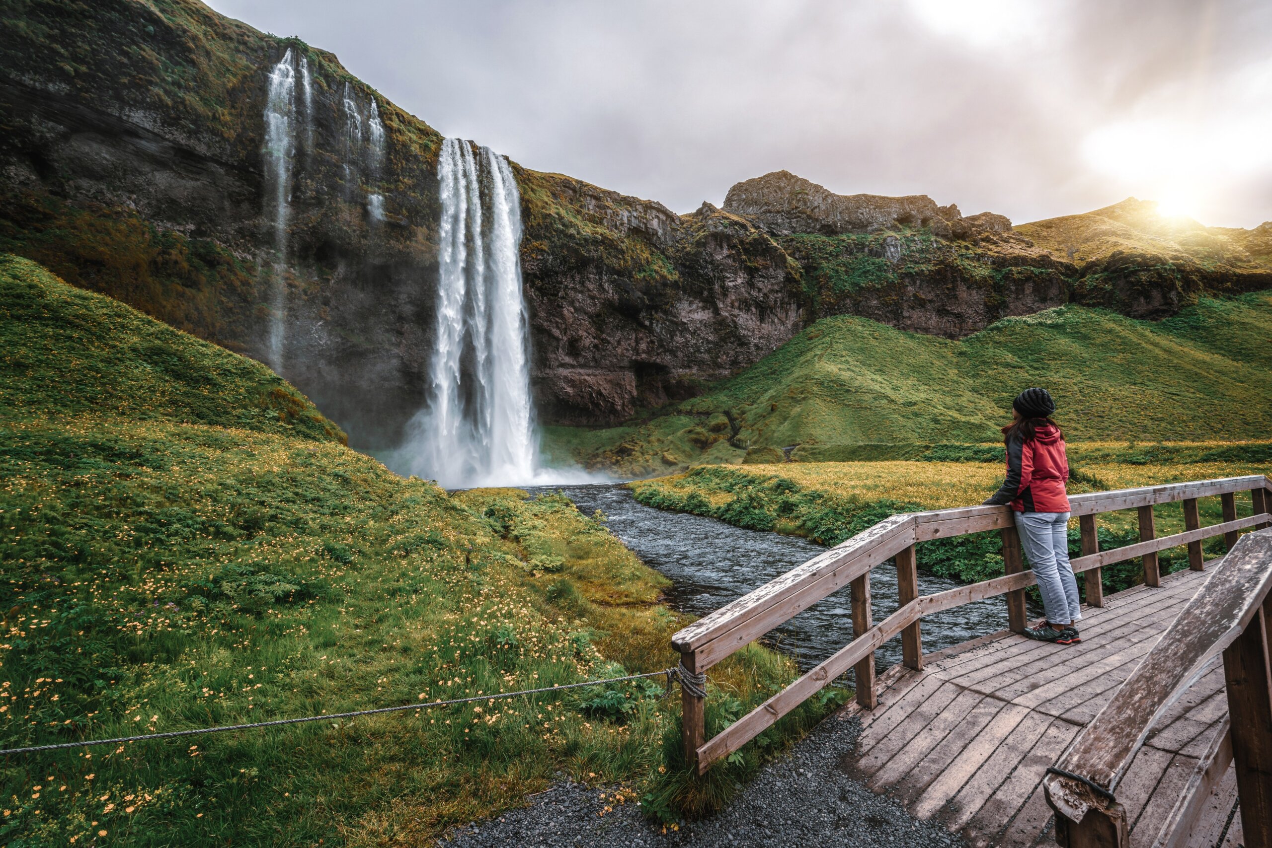 Woman traveler at Magical Seljalandsfoss Waterfall in Iceland located near ring road of South Iceland. Majestic and picturesque, it is one of most photographed breathtaking place of Iceland wilderness
