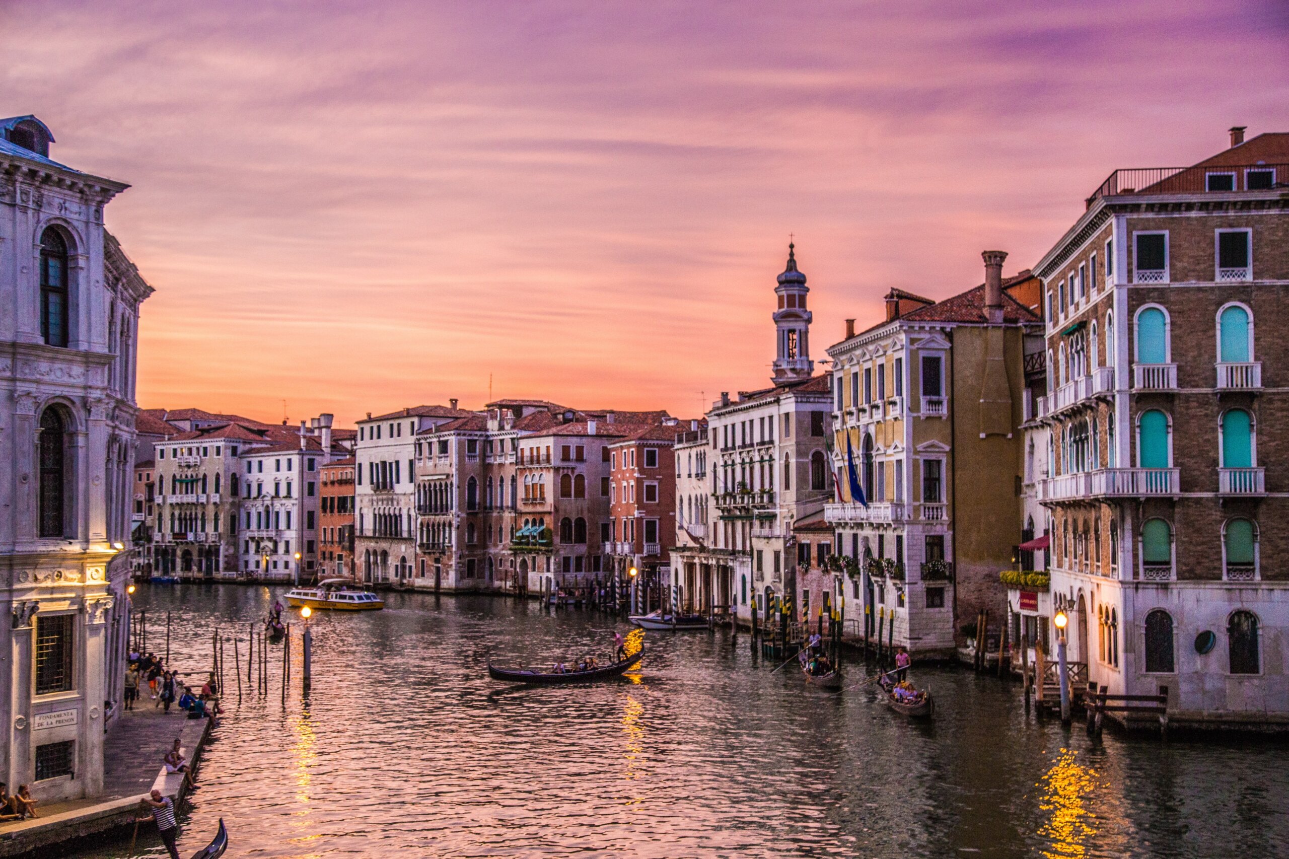 Sunset over the Grand Canal in Venice with gondolas and historic buildings, travel guide to where to eat, stay, and play.