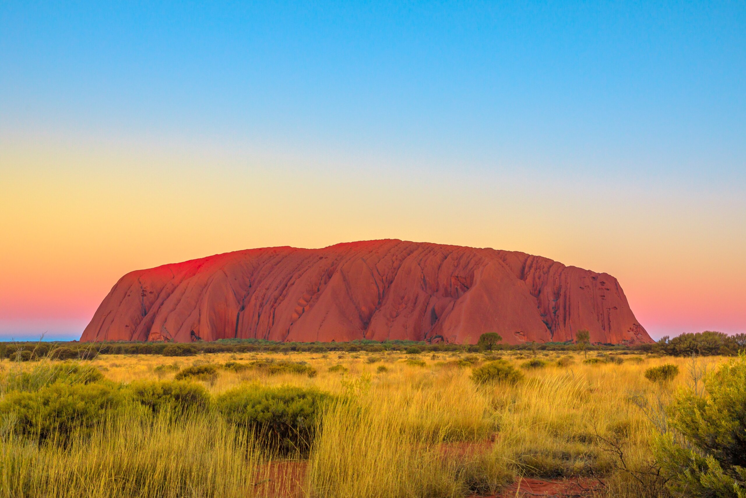 Uluru or Ayers Rock after sunset. The iconic monolith at twilight in Uluru-Kata Tjuta National Park, Australia, Northern Territory. Aboriginal land in Australian outback or Red Centre.
