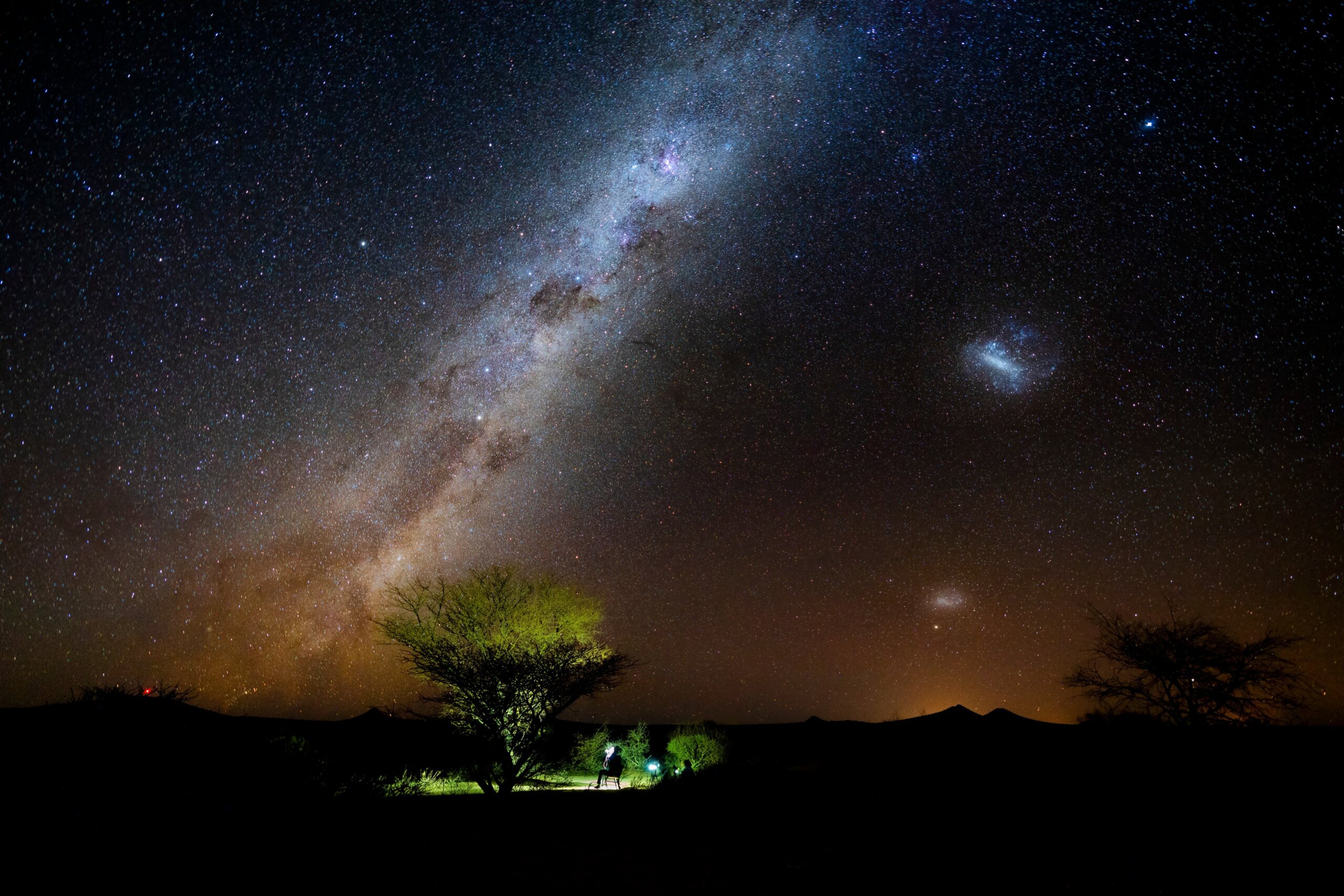 Photographer and traveler take photo beautiful starry night at alone tree in Namibia. Night landscape milky way photograph.
