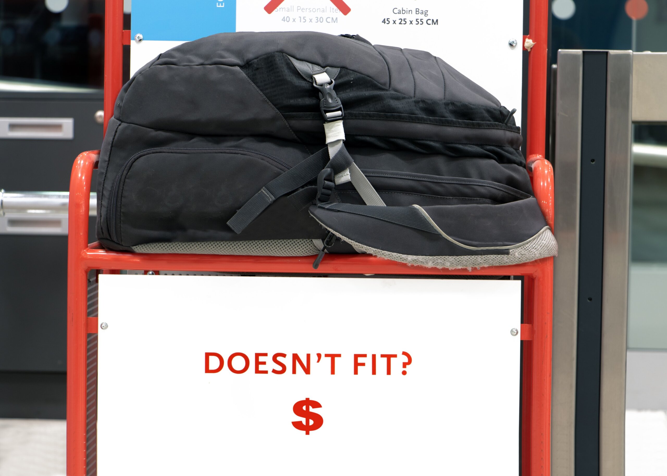 U.S. travel rules 2025: The large backpack lying on a control cage for measure size of carry on luggage. Checking baggage size at the airport.
