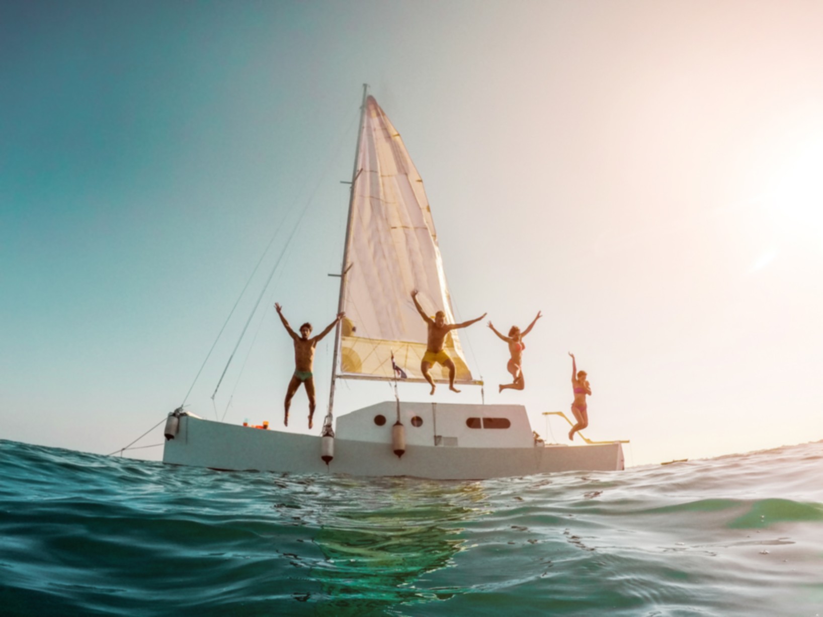 Blurred crazy friends diving from sailing boat into the sea - Young people jumping inside ocean in summer vacation - Defocused image - Travel and fun concept - Fisheye lens distortion