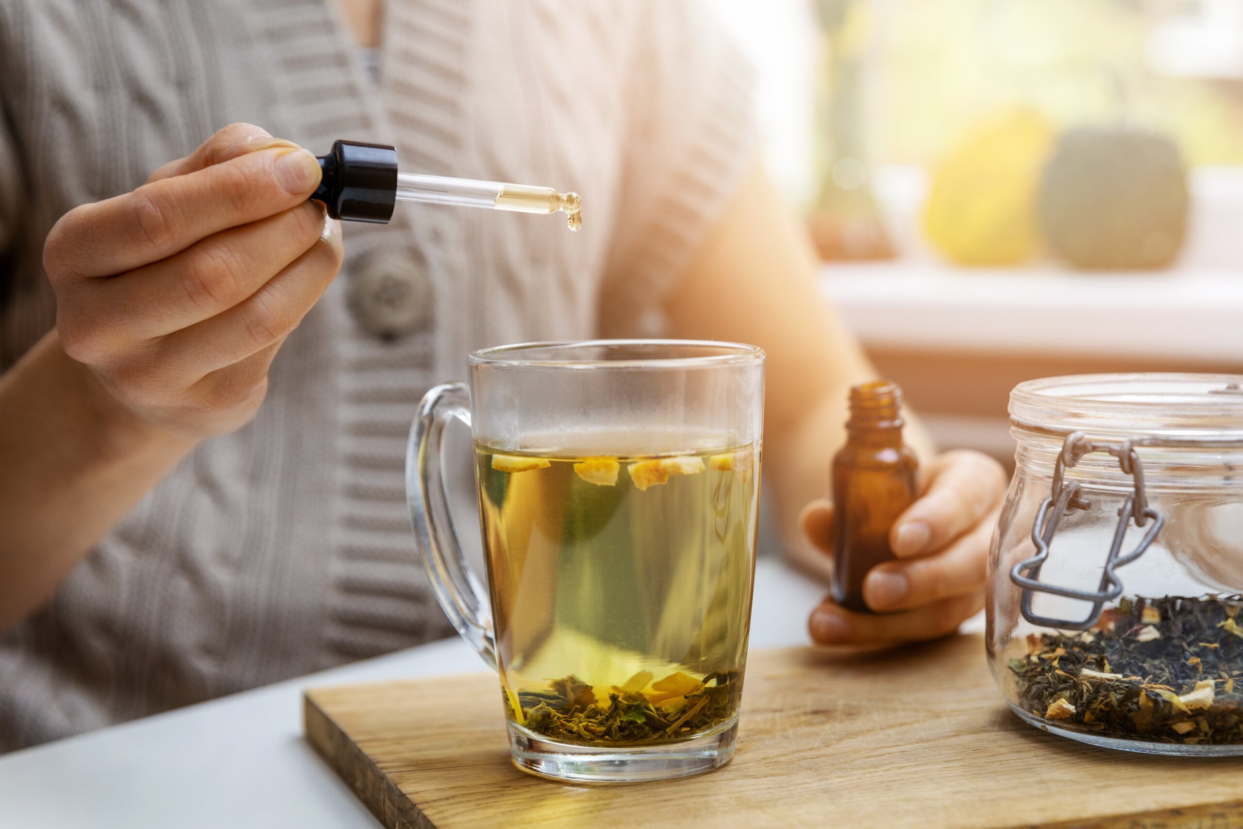 dietary supplements and vitamins - woman adding drop of cbd oil in cup of tea with pipette. anti stress
