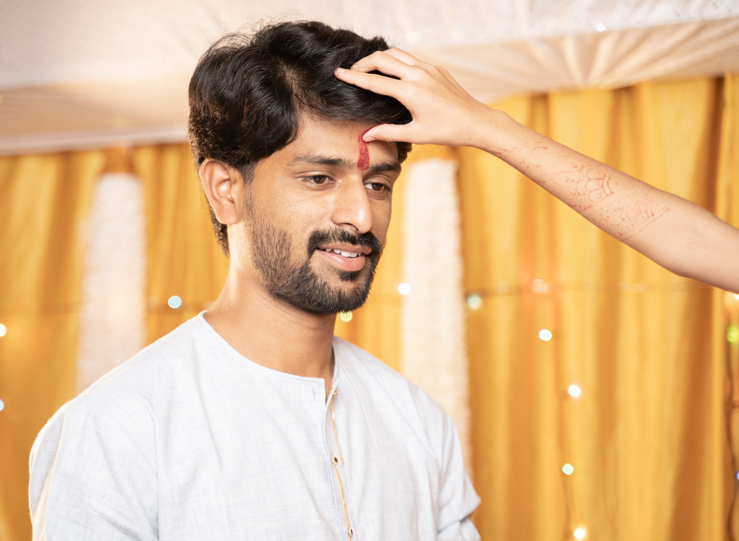 Close up Hands of Sister applying Tilak or mark to forehead of elder Brother during Bhai Dooj or Bhaubeej Indian religious festival
