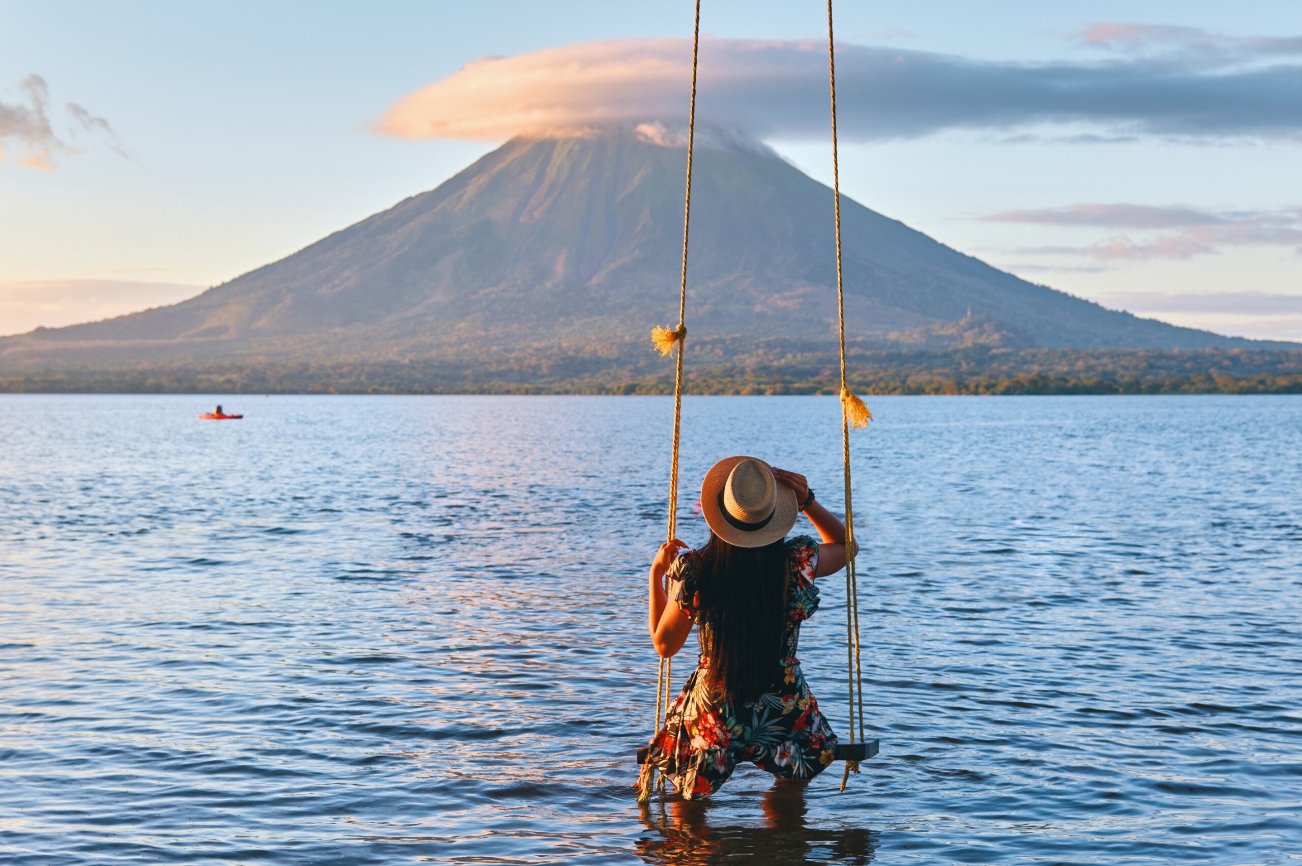 Solo female traveler on a swing overlooking Volcano Concepción in Ometepe, Nicaragua at sunset.