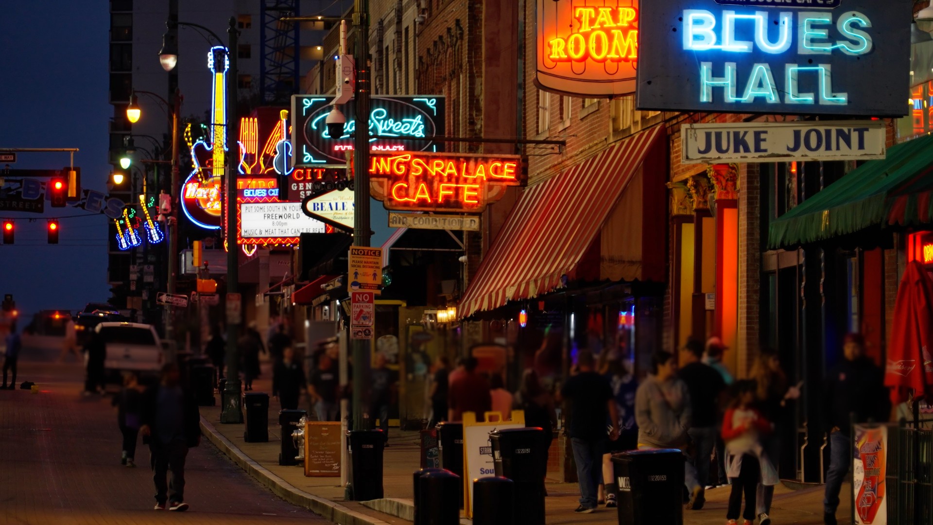 The neon lights form the bars and cafes of Beale Street in Memphis are reflected in the rainy street at night
