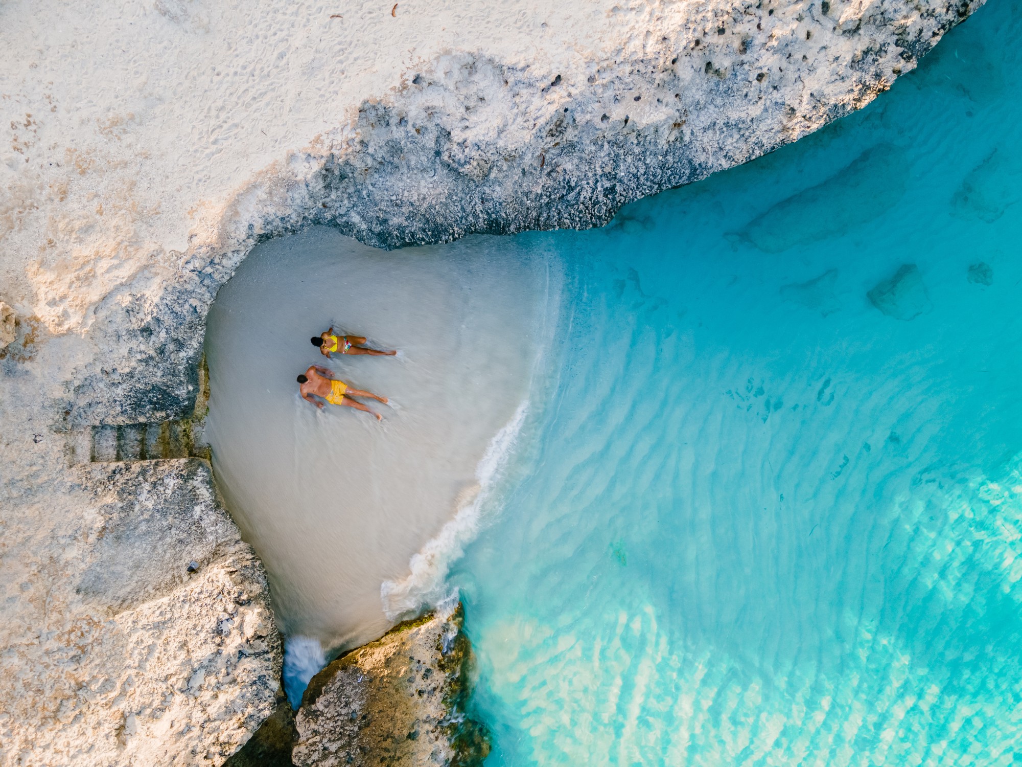 a couple of men and women on the beach of Tres Trap Aruba Caribbean Island. Tres Trapi Bay is popular with locals for snorkeling and diving in the turqouse colored ocean