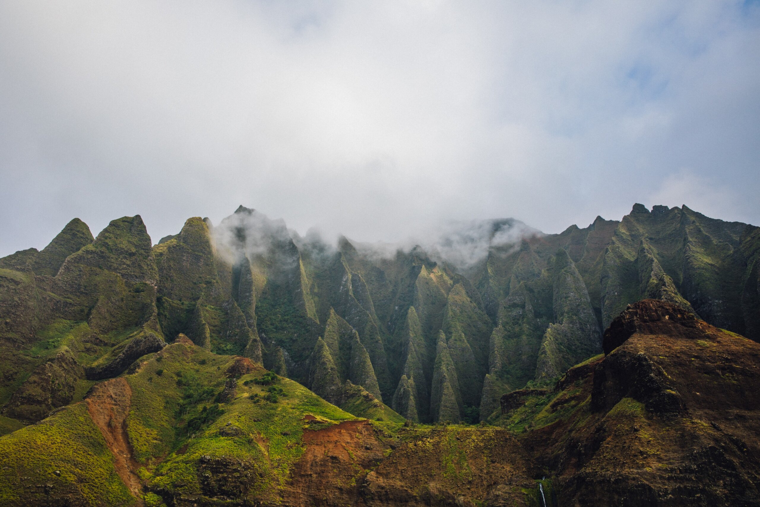 Fog over the mountains of the NaPali Coastline on the island of Kauai, Hawaii on a cloudy day from a sunsets boat cruise