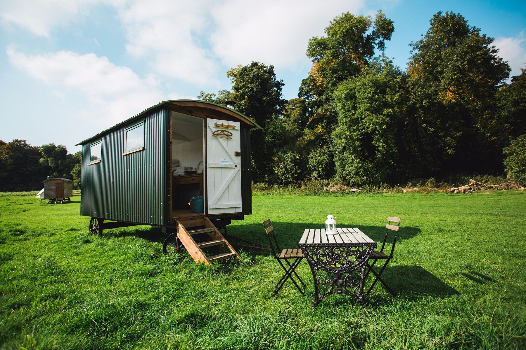 Shepherd’s hut with an open door and bistro table set on a grassy field at Rock Farm Slane in County Meath, Ireland.
