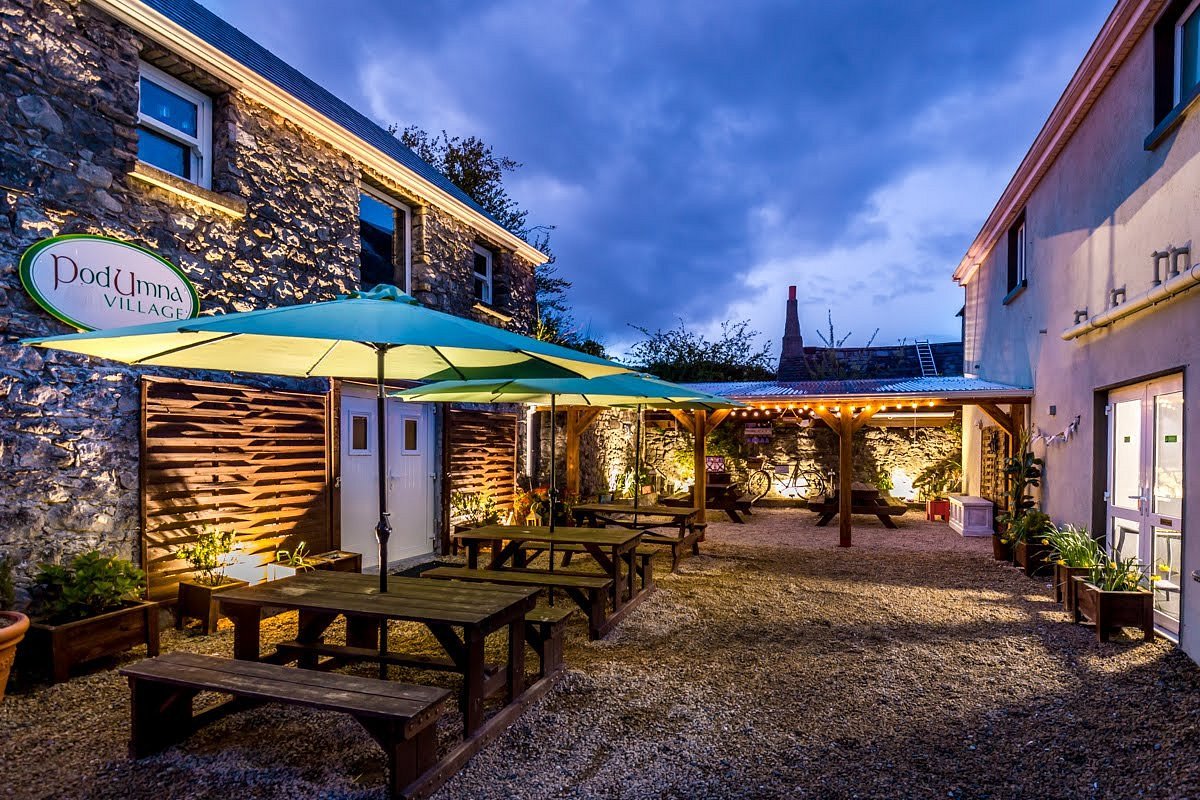 Charming courtyard with picnic tables and string lights at Podumna Village glamping site in Portumna, County Galway.