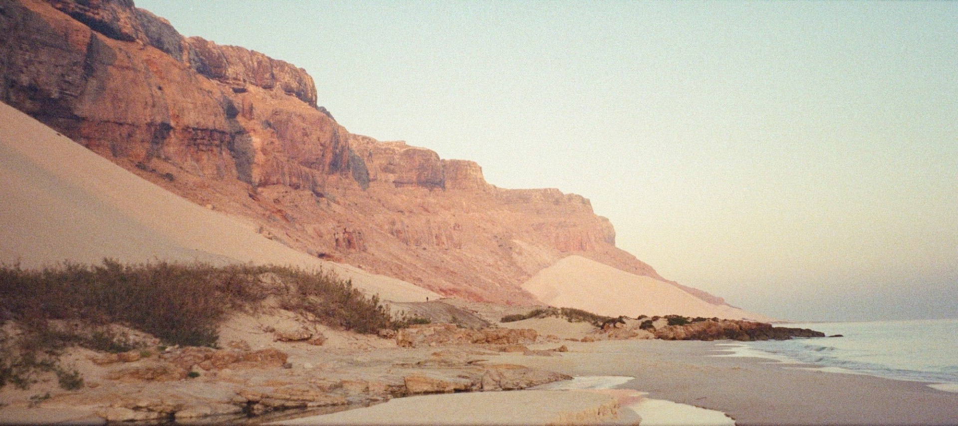 Remote Socotra Island coastline with cliffs and sandy beach at sunrise