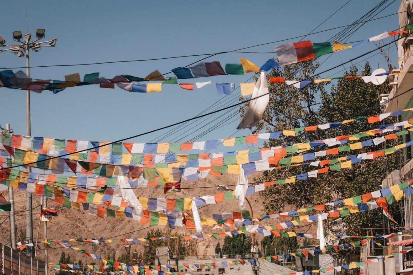 Colorful prayer flags hanging above a street in India, representing cultural diversity and traditions.