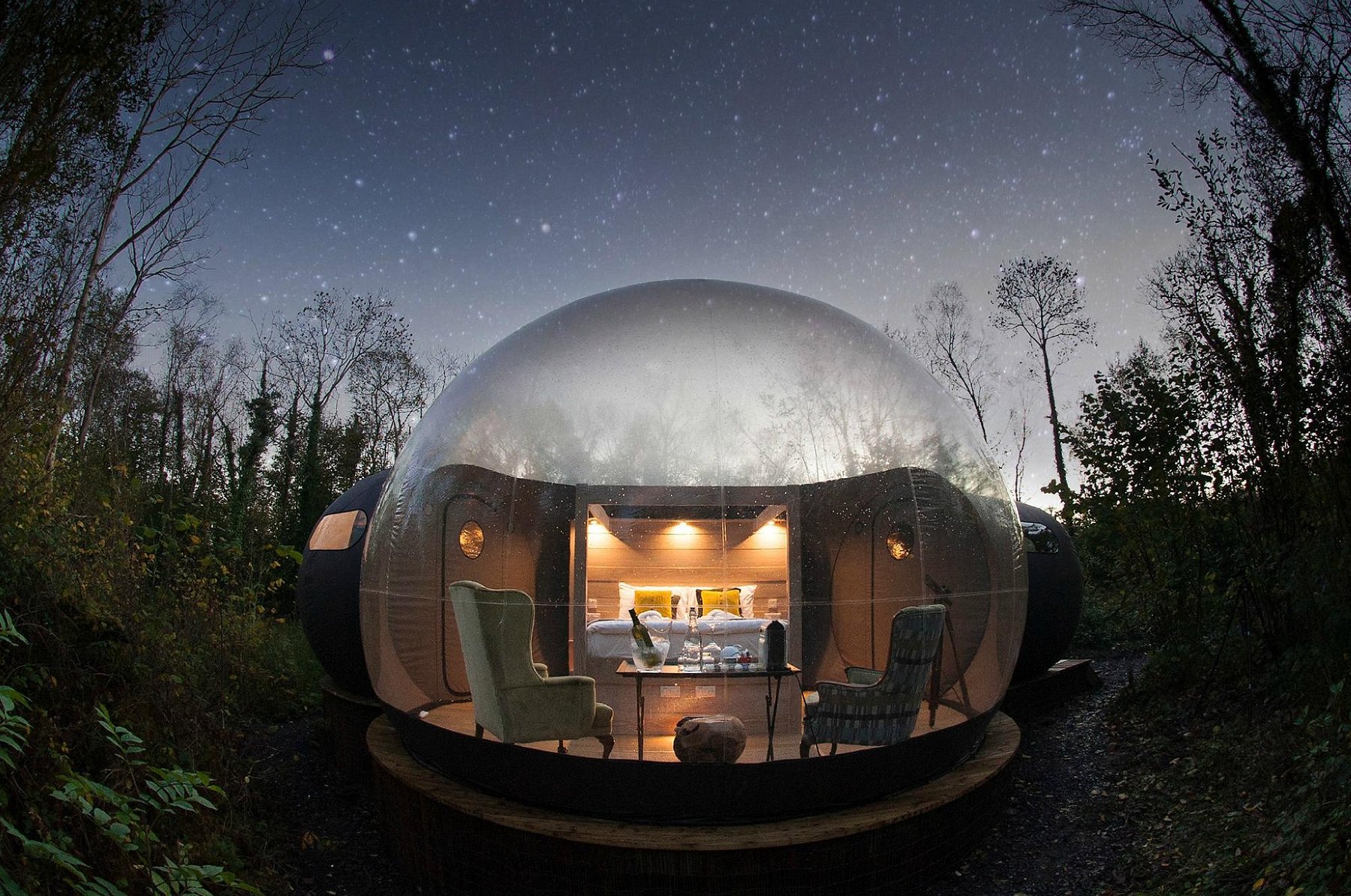 Transparent luxury bubble dome glowing at night in the forest at Finn Lough in County Fermanagh, Ireland.