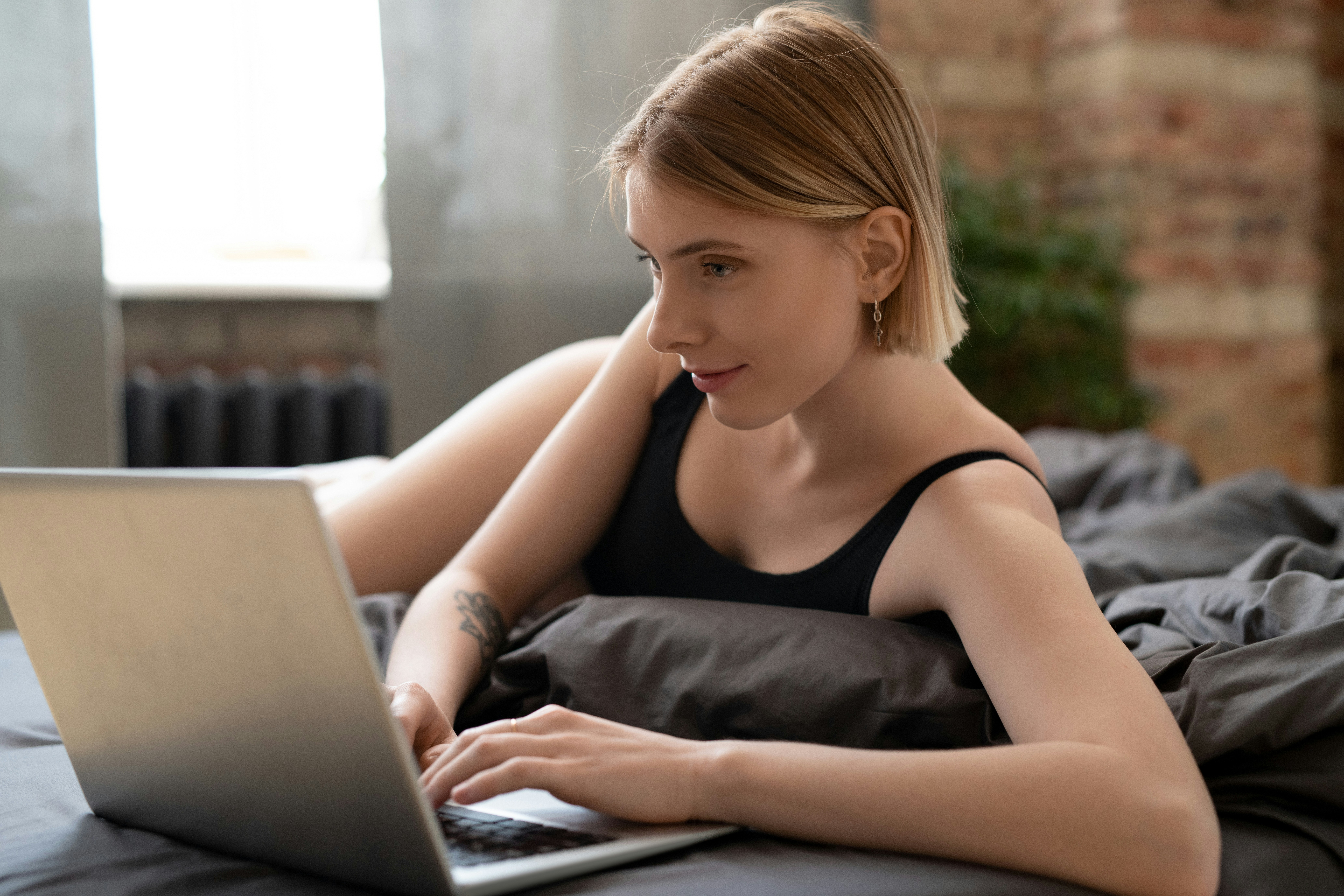 Woman on laptop in a cozy room booking last-minute travel deals, highlighting flexibility and quick decision-making.