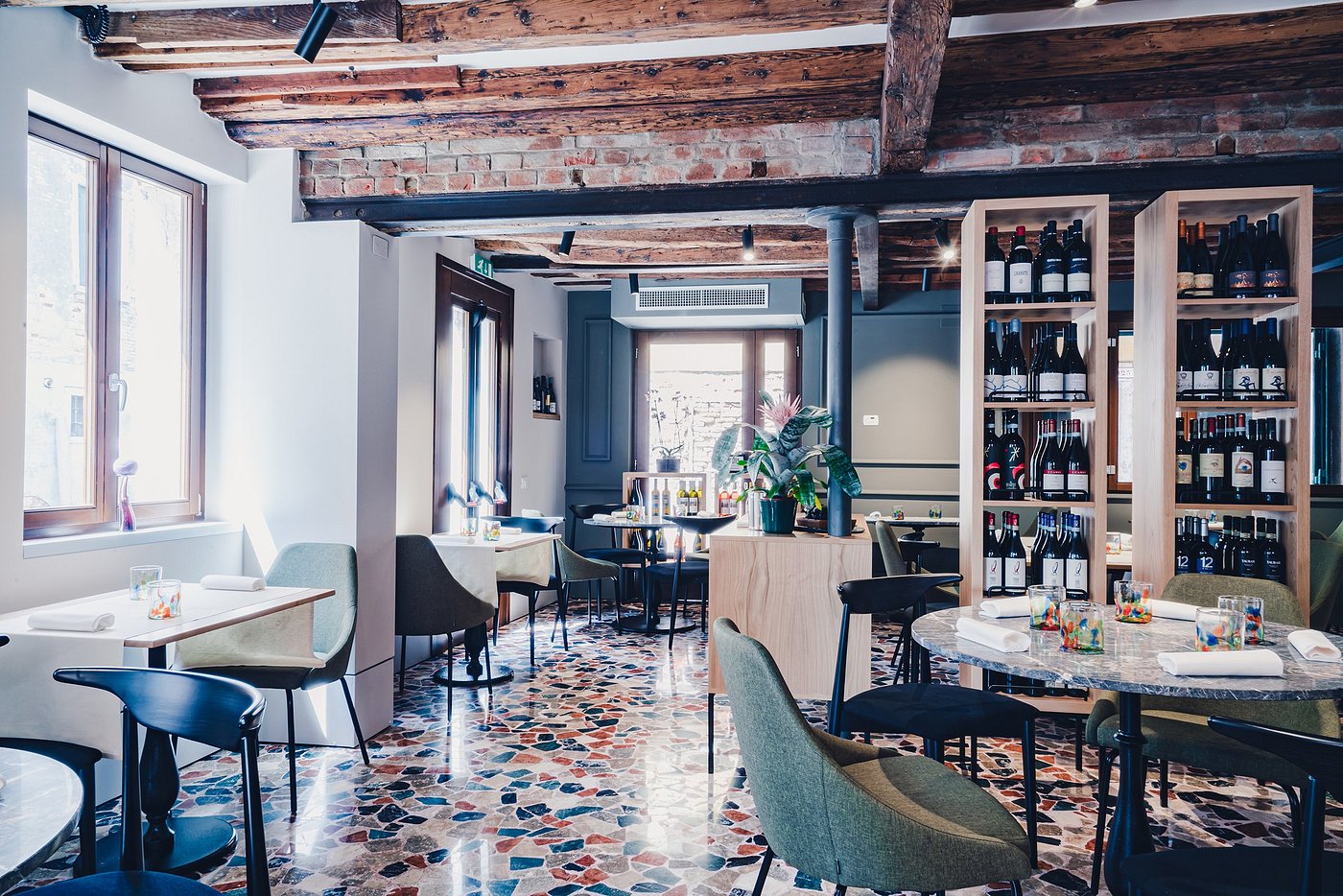 Dining room at Michelin-starred Ristorante Wistèria in San Polo, Venice, with terrazzo floors and wine displays.