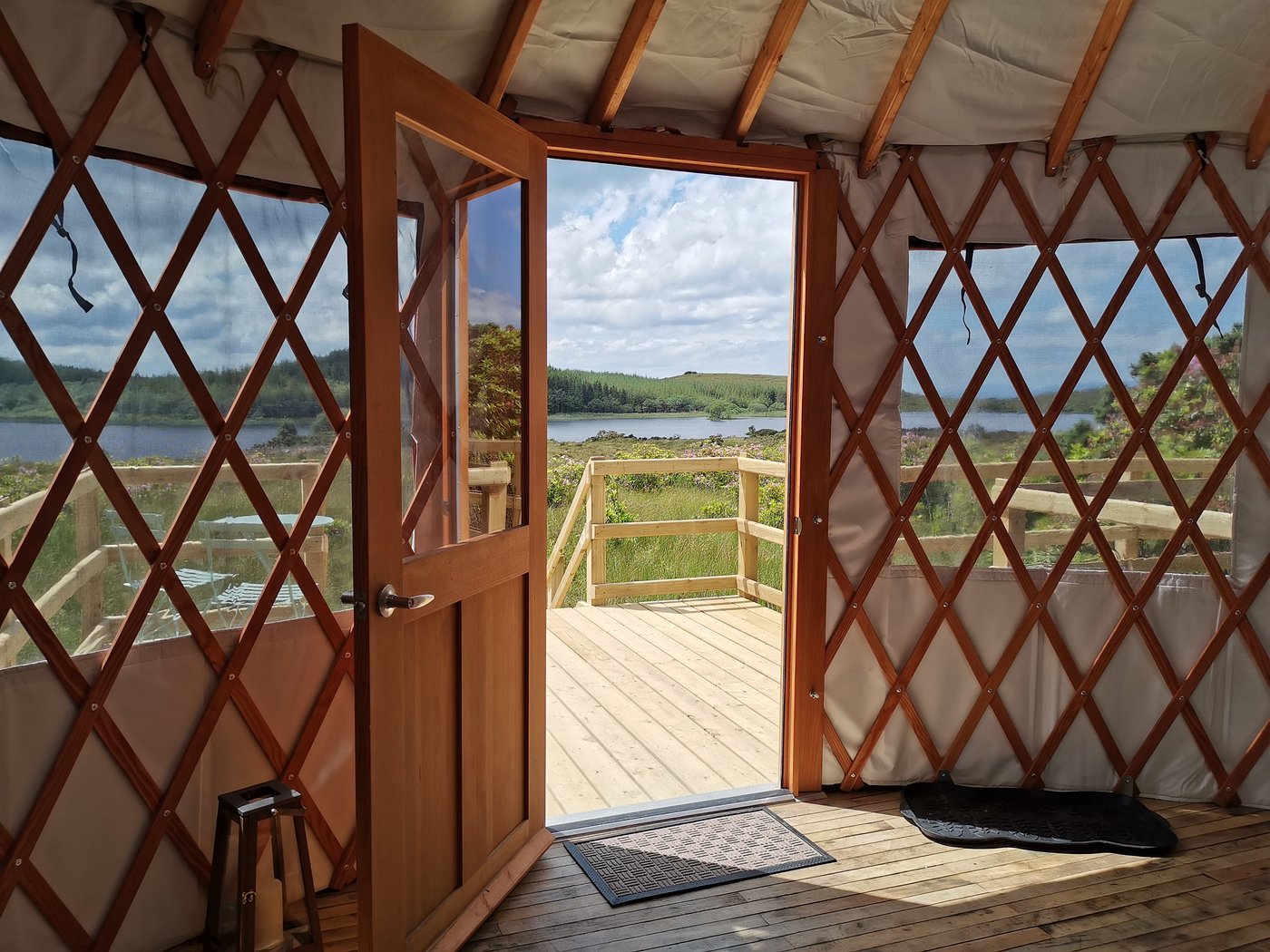 Wooden yurt interior with an open door leading to a scenic lake view at Lough Mardal Lodge in County Donegal, Ireland.