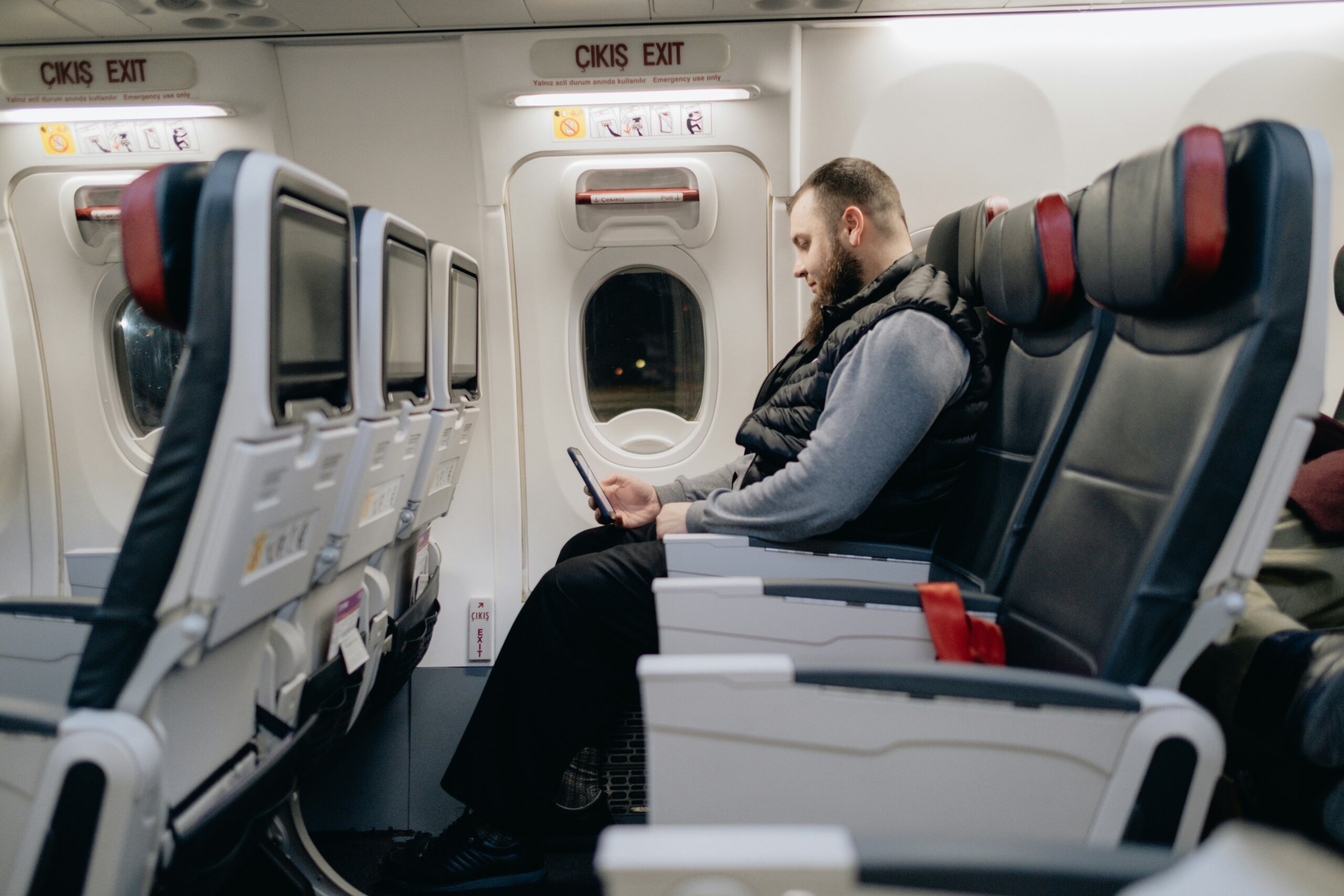 Passenger seated comfortably in an exit row demonstrating smart spending airplane comfort tips to feel less crowded on a plane.