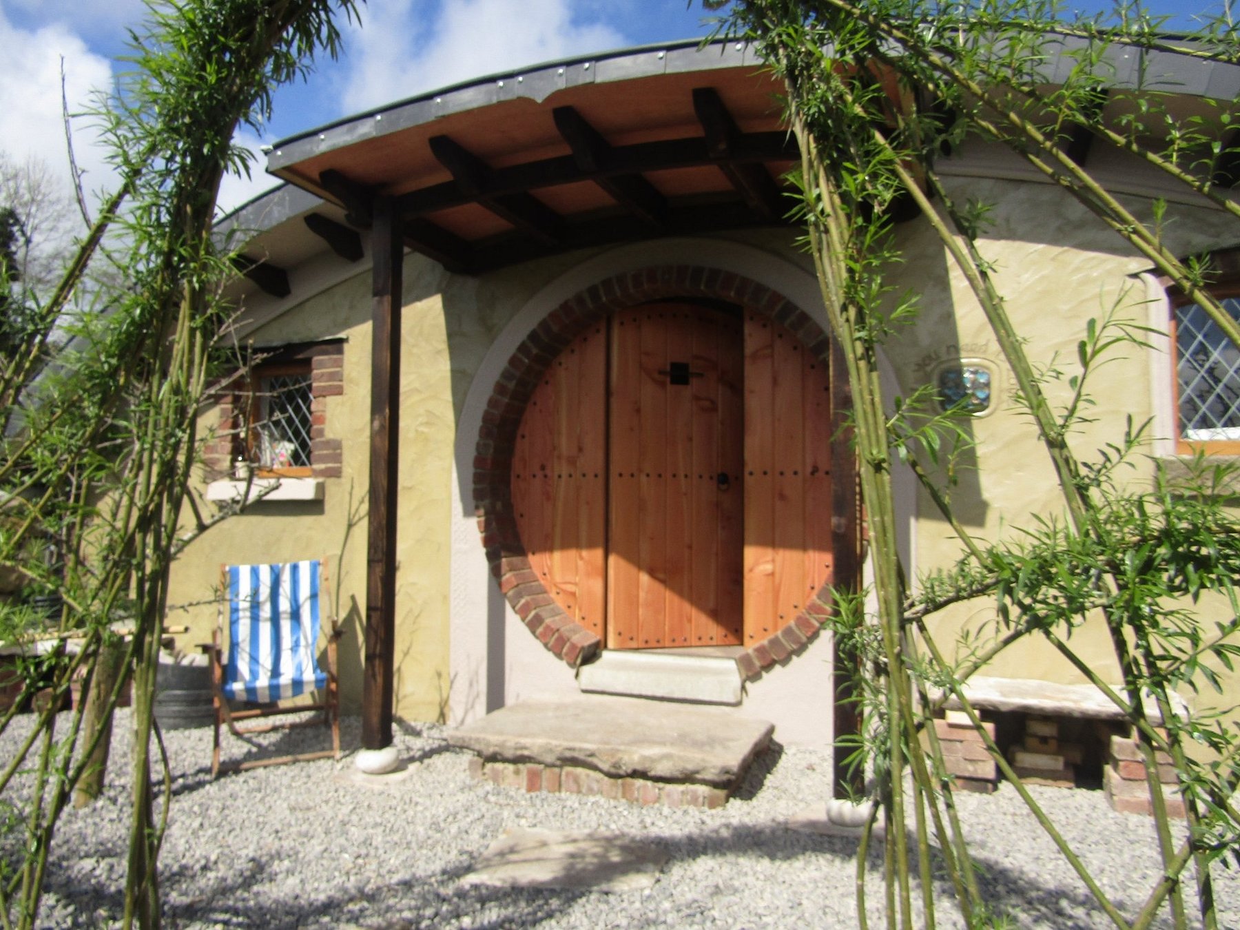 Hobbit-style round wooden door entrance surrounded by greenery at Pink Apple Orchard glamping site in County Leitrim, Ireland.