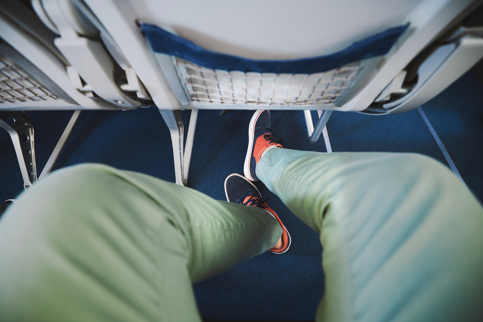 Passenger stretching legs in an exit row seat showing how to feel less crowded on a plane with extra legroom options.