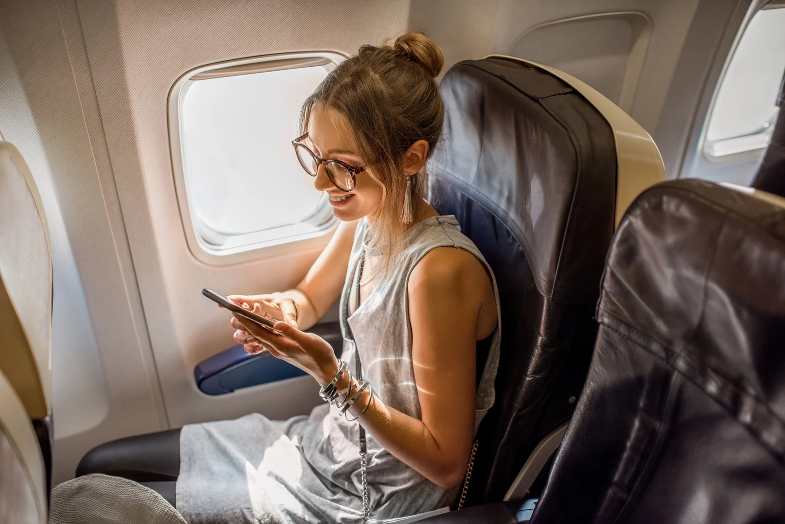 Woman enjoying extra space with a blocked middle seat, one of the best airplane comfort tips to feel less crowded on a plane.