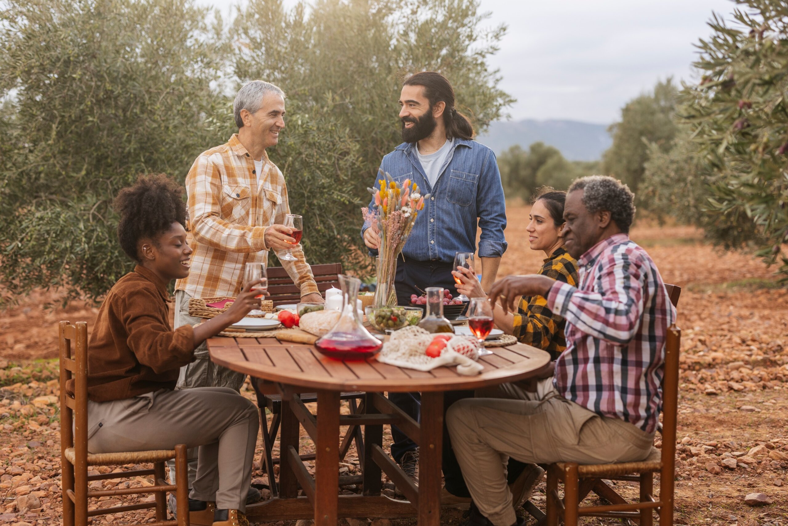 Farmers enjoying lunch together in olive grove after harvest
