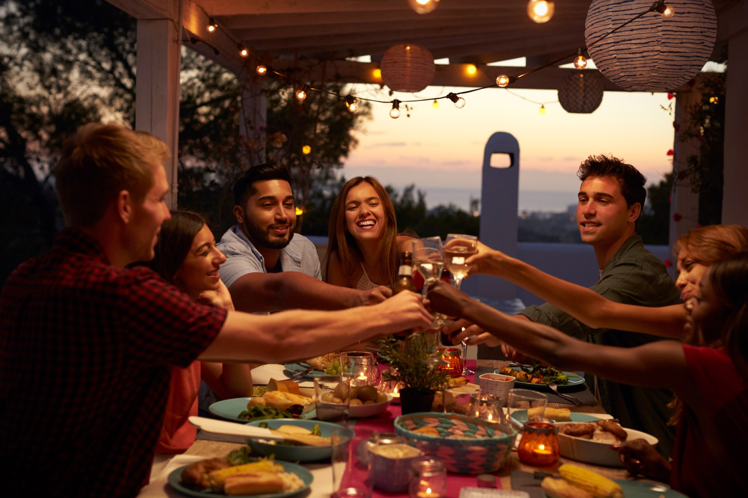 Friends make a toast at a dinner party on a patio, close up
