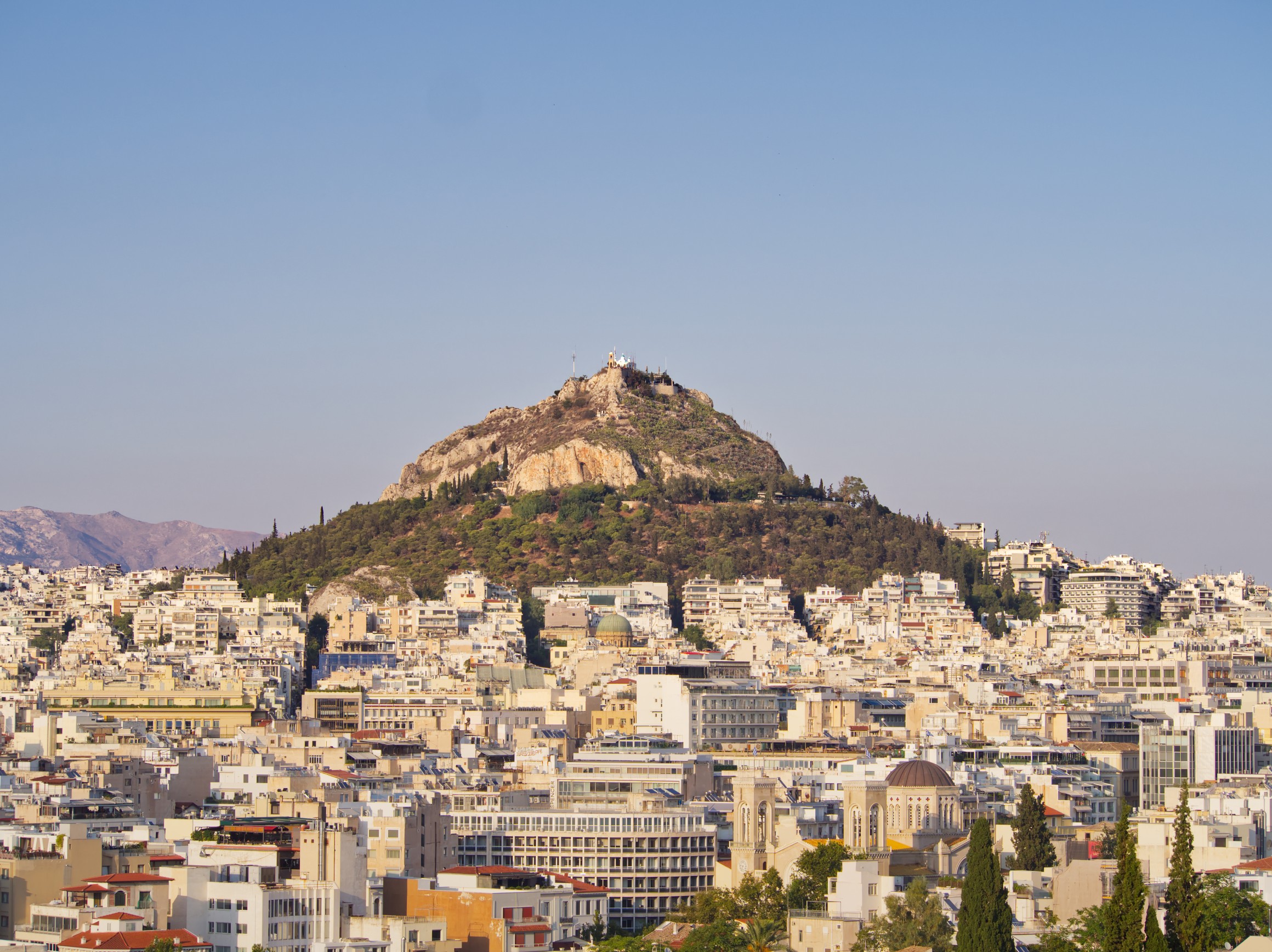 European Overtourism Impact - Athens, Greece, with densely packed buildings and Lycabettus Hill dominating the skyline