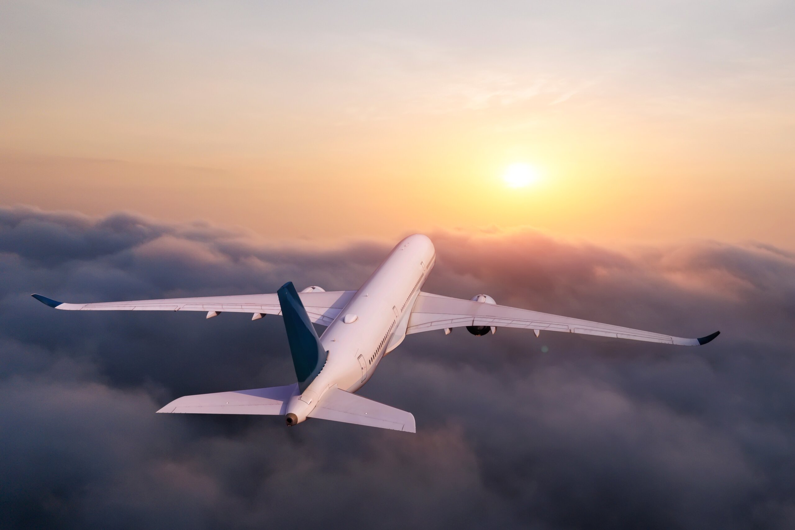 How to deal with holiday airport wait times during government shutdown travel delays: Passenger plane flies gliding above the clouds in the early morning with a beautiful sun disk above the horizon in warm colors