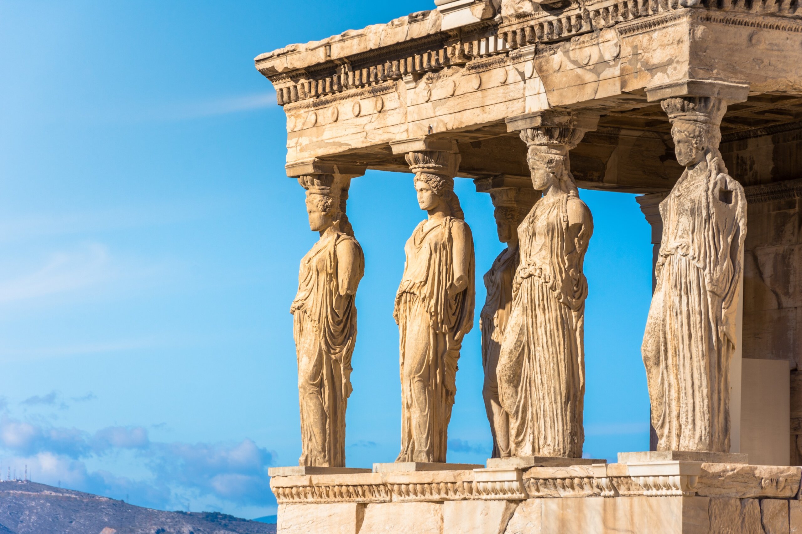 Karyatides statues of the Erechtheion on the Acropolis in Athens, Greece, with blue sky background.