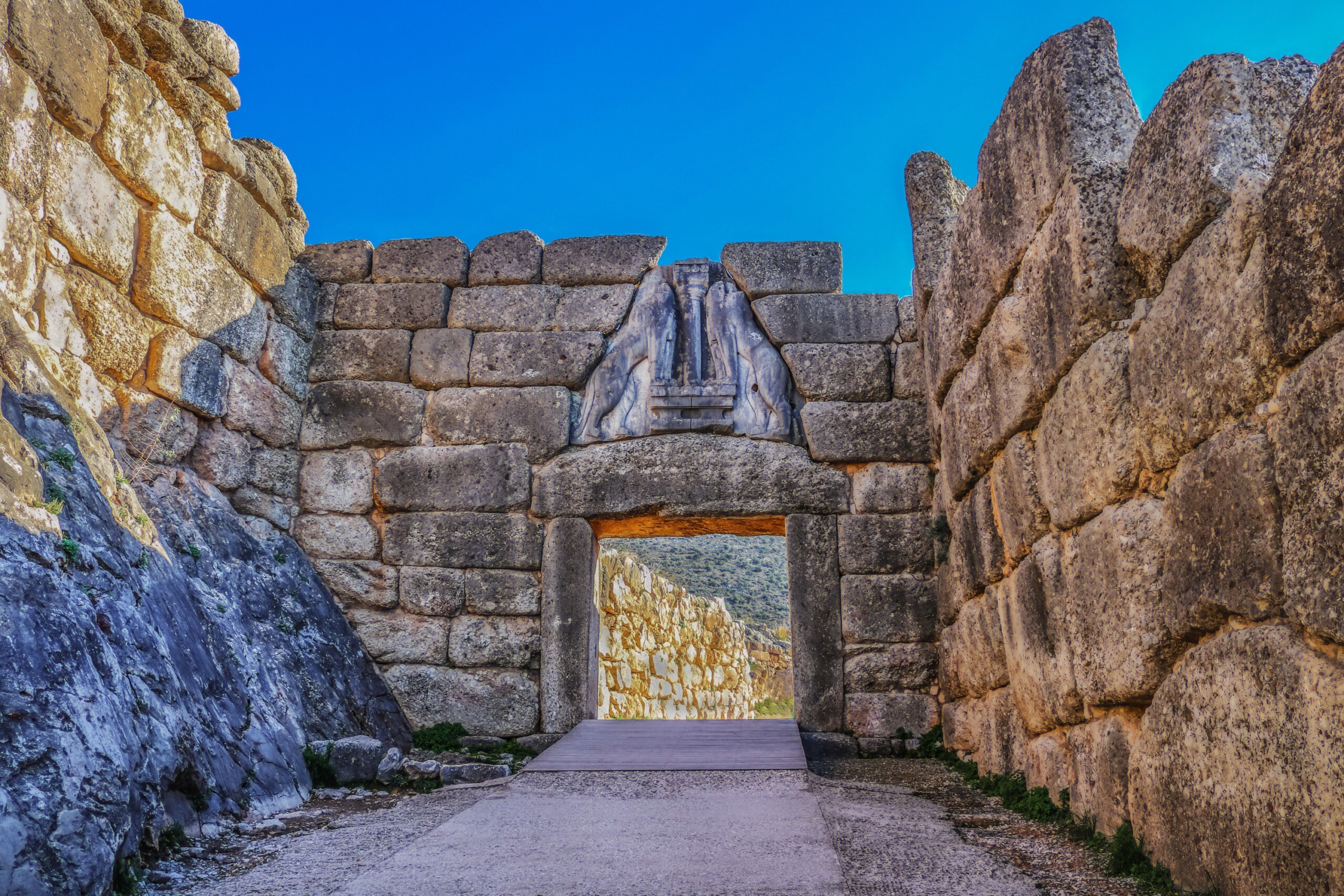 Bright Greek sunlight shines of rock wall of ancient Mycenae on the road up to the famous Lions Gate into the hill fortress where the armies of Troy originated
