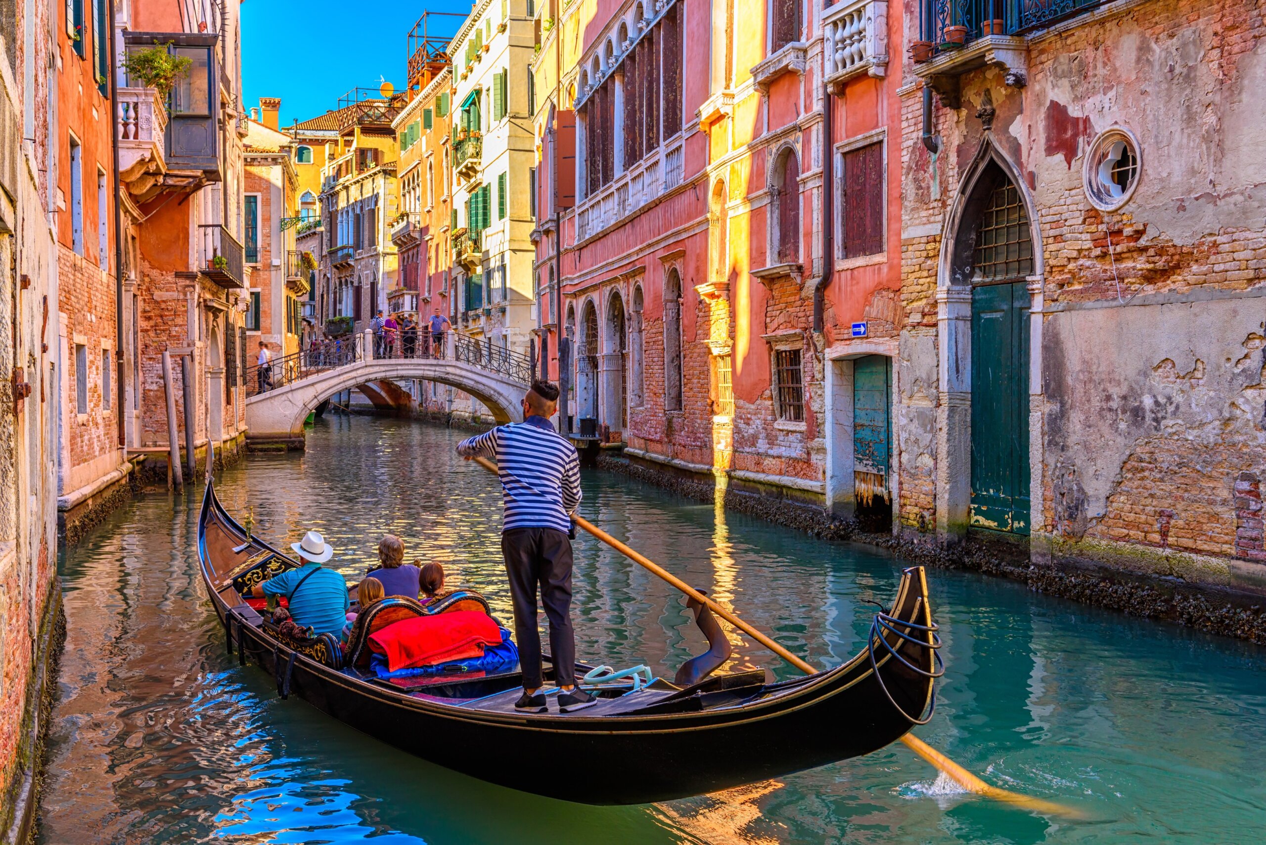 European Overtourism - Narrow canal with gondola and bridge in Venice, Italy. Architecture and landmark of Venice.