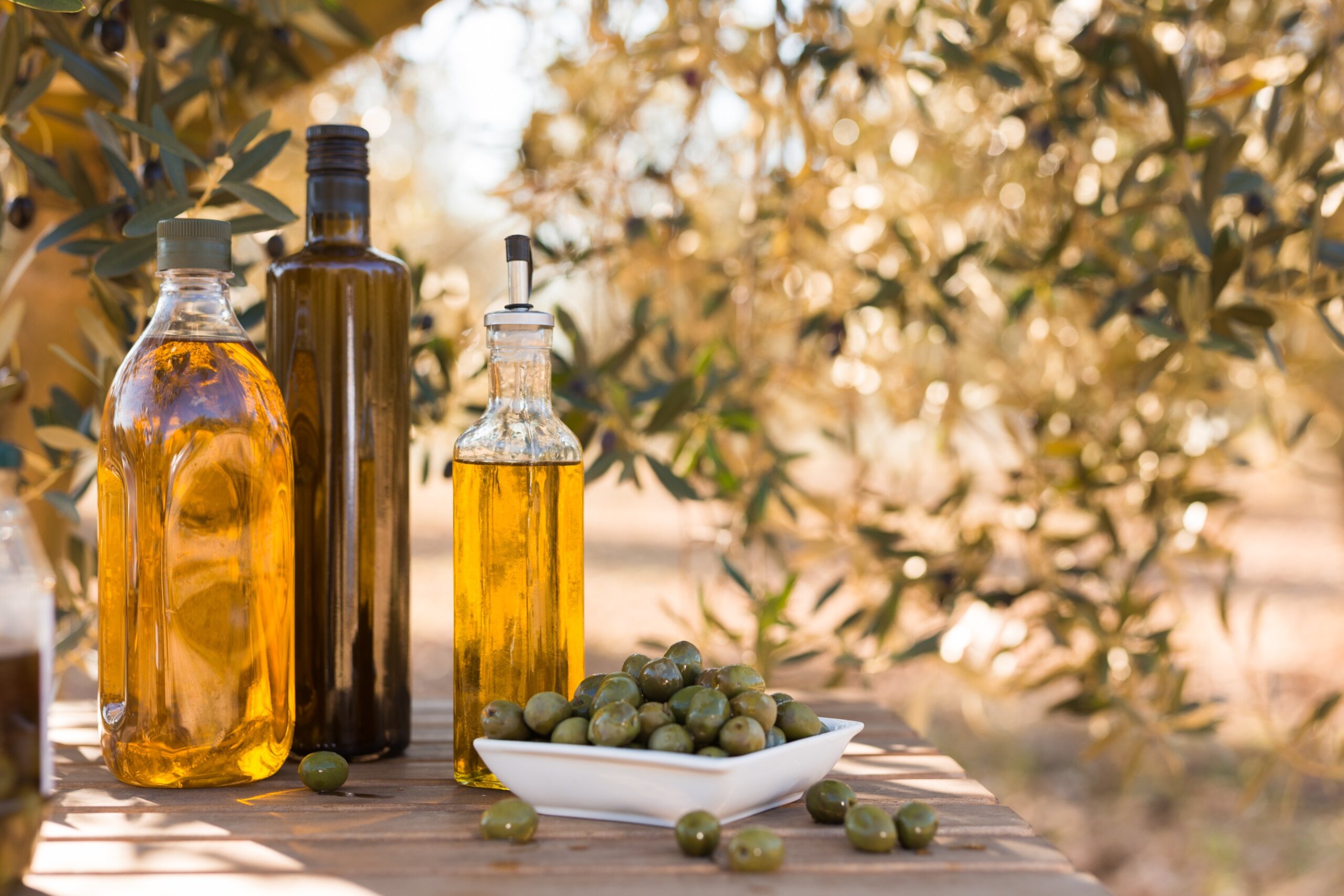 green olives and oil on table in olive grove
