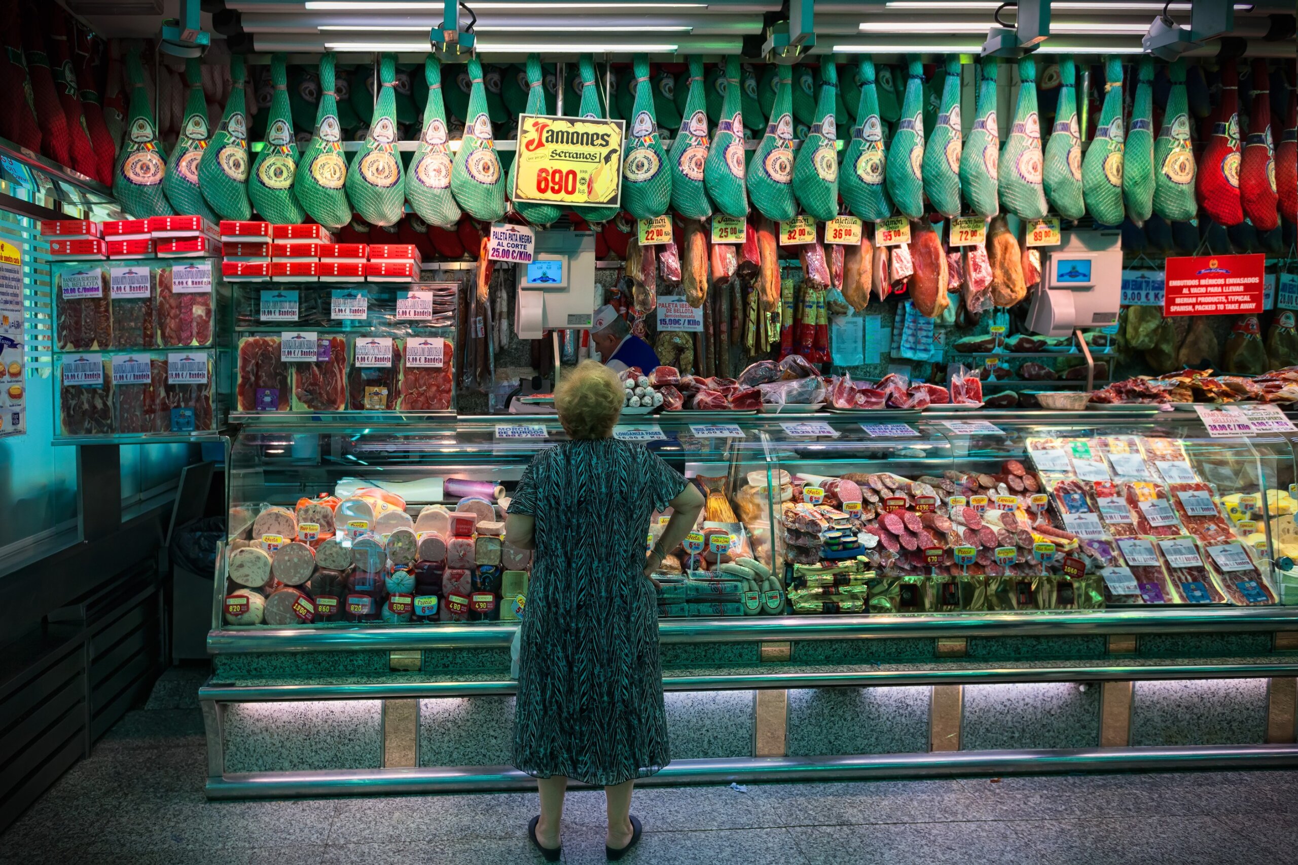 Spain, Barcelona - 2019. A woman in a butcher shop chooses jamon.
