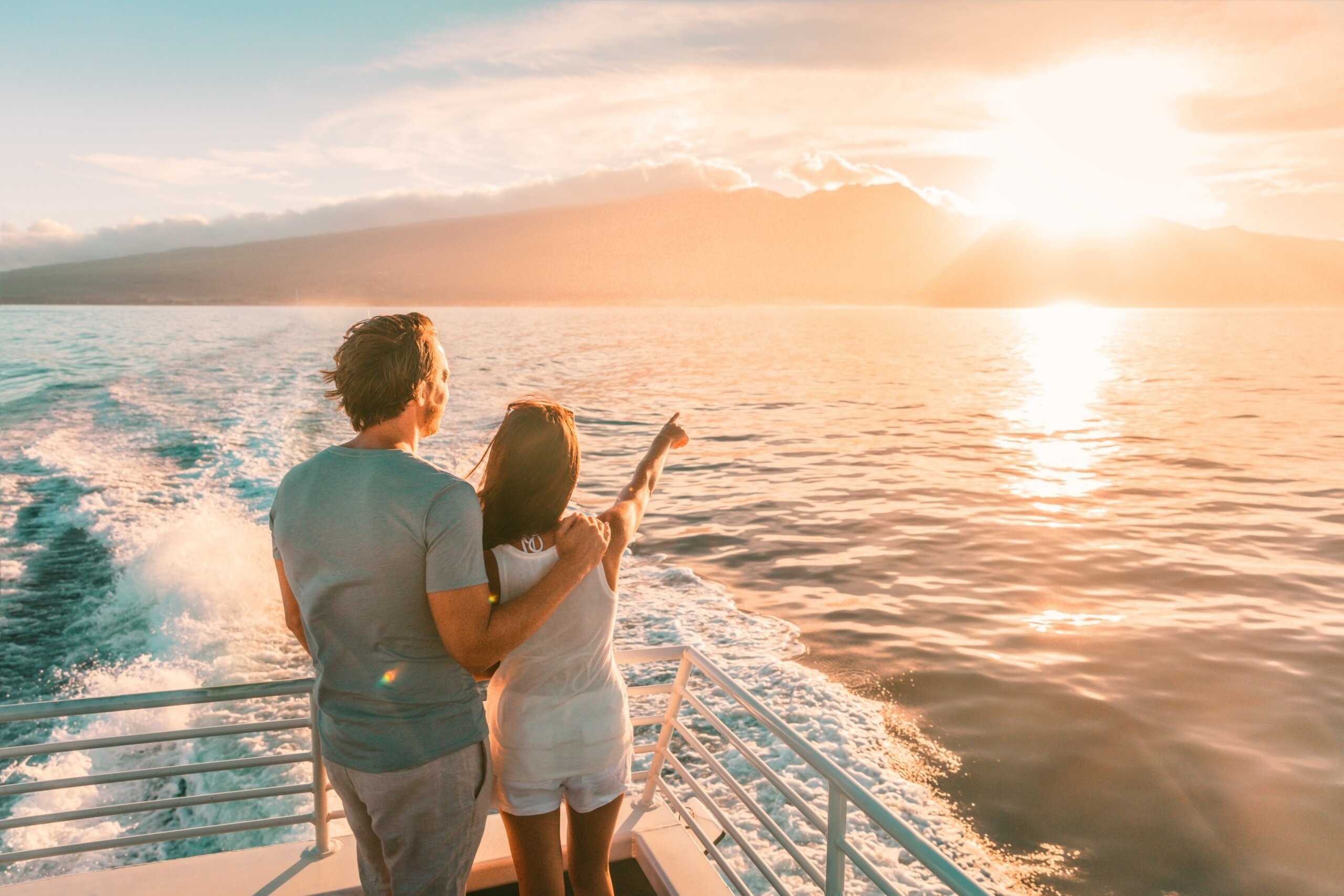 Cruise ship vacation travel tourists couple watching sunset on deck summer travel. lady pointing at sun to man tourist relaxing on Caribbean holidays.