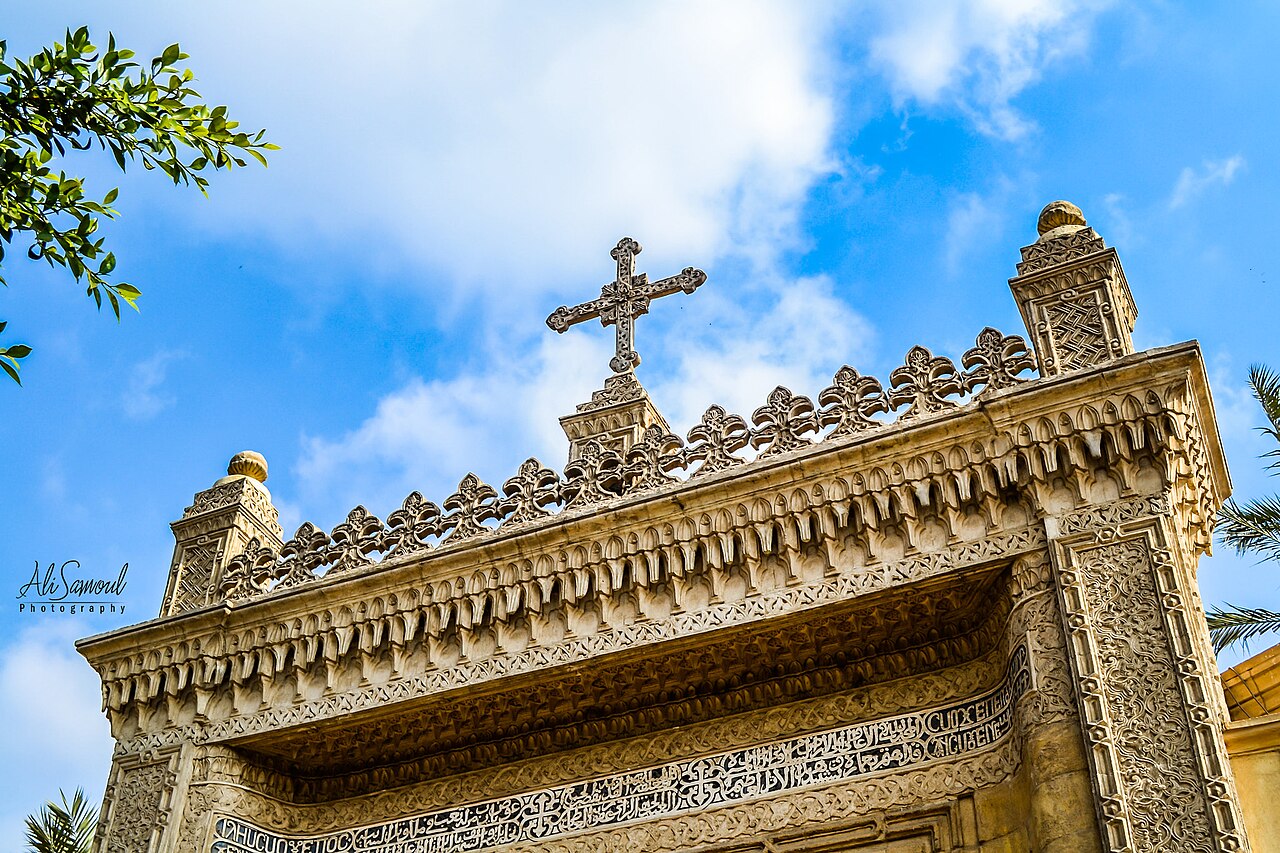 The Hanging (The Suspended) Church is named for its location above a gatehouse of Babylon Fortress, the Roman fortress in Coptic Cairo (Old Cairo); its nave is suspended over a passage. The church is approached by twenty nine steps; early travelers to Cairo dubbed it "the Staircase Church."[3] The land surface has risen by some six metres since the Roman period[why?] so that the Roman tower is mostly buried below ground, reducing the visual impact of the church's elevated position. The entrance from the street is through iron gates under a pointed stone arch. The nineteenth-century facade with twin bell towers is then seen beyond a narrow courtyard decorated with modern art biblical designs. Up the steps and through the entrance is a further small courtyard leading to the eleventh-century outer porch.