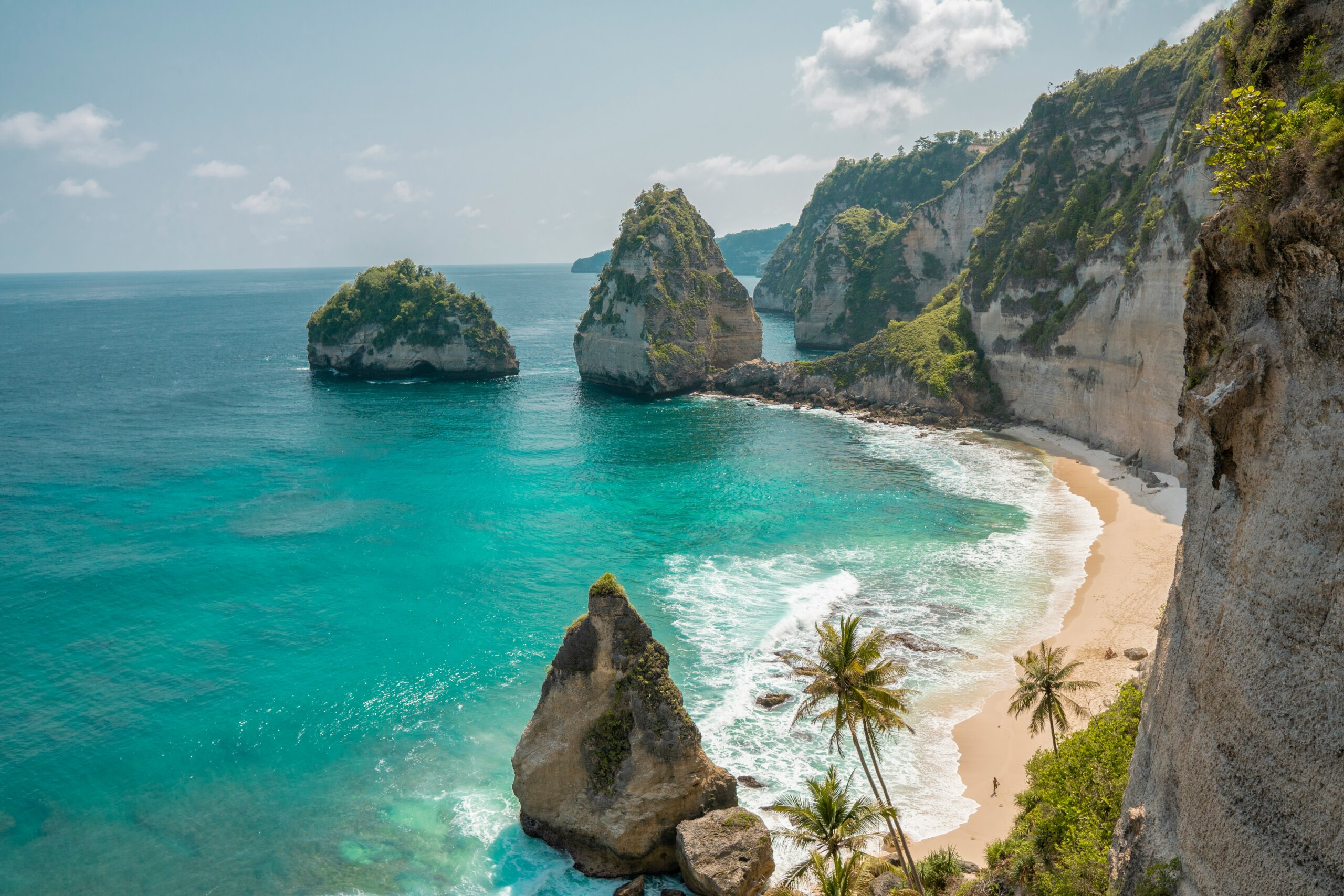 Bali beach with turquoise water and cliffs under sunny skies, symbolizing tropical travel and island adventures.