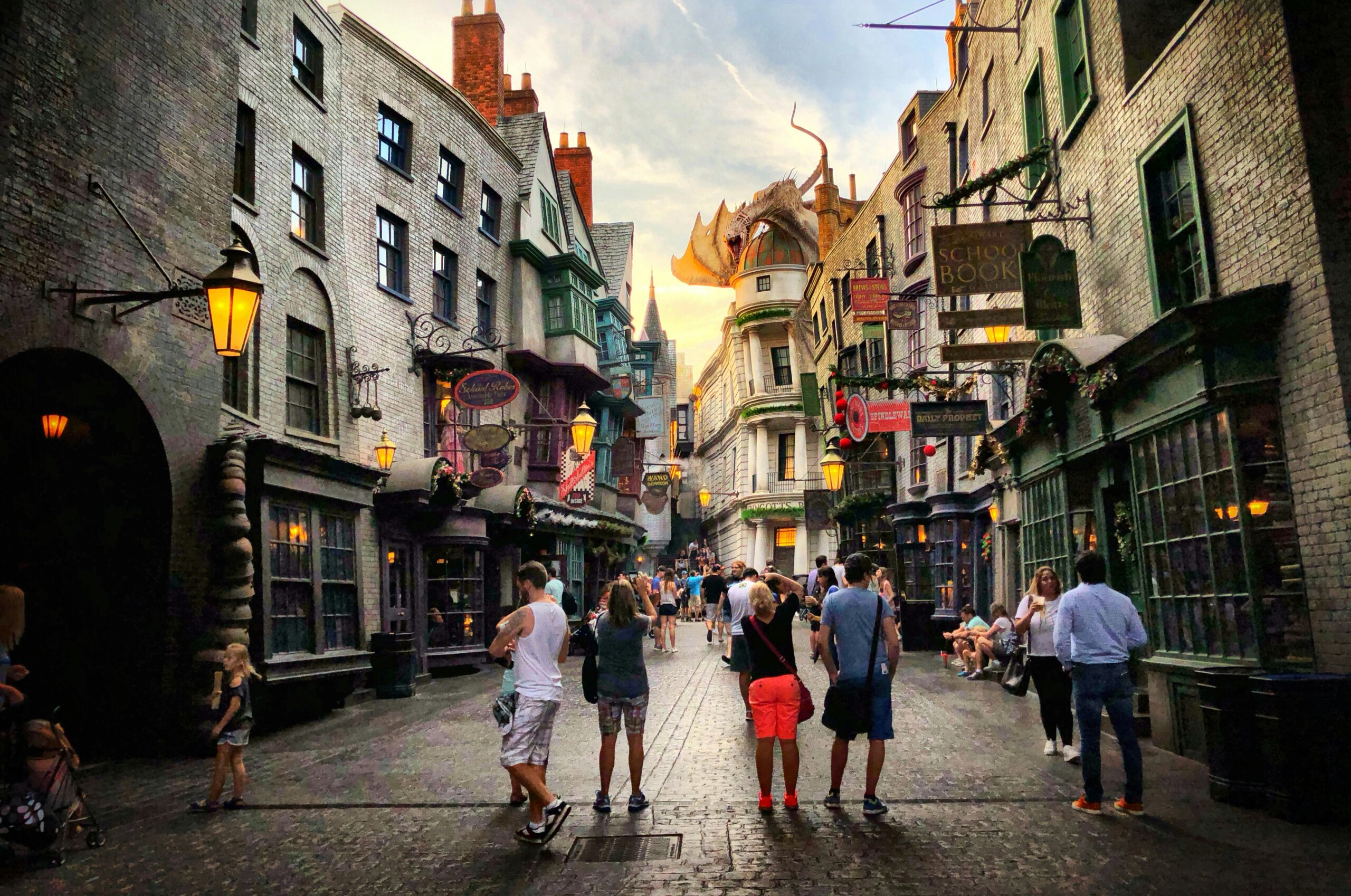 Crowds walking along a detailed, immersive themed street at a busy U.S. theme park.
