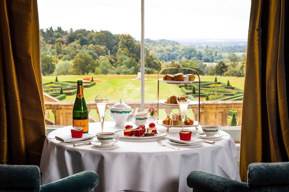 Cliveden House dining room table stocked with champagne and sweet treats with a stunning view overlooking regal estate gardens.
