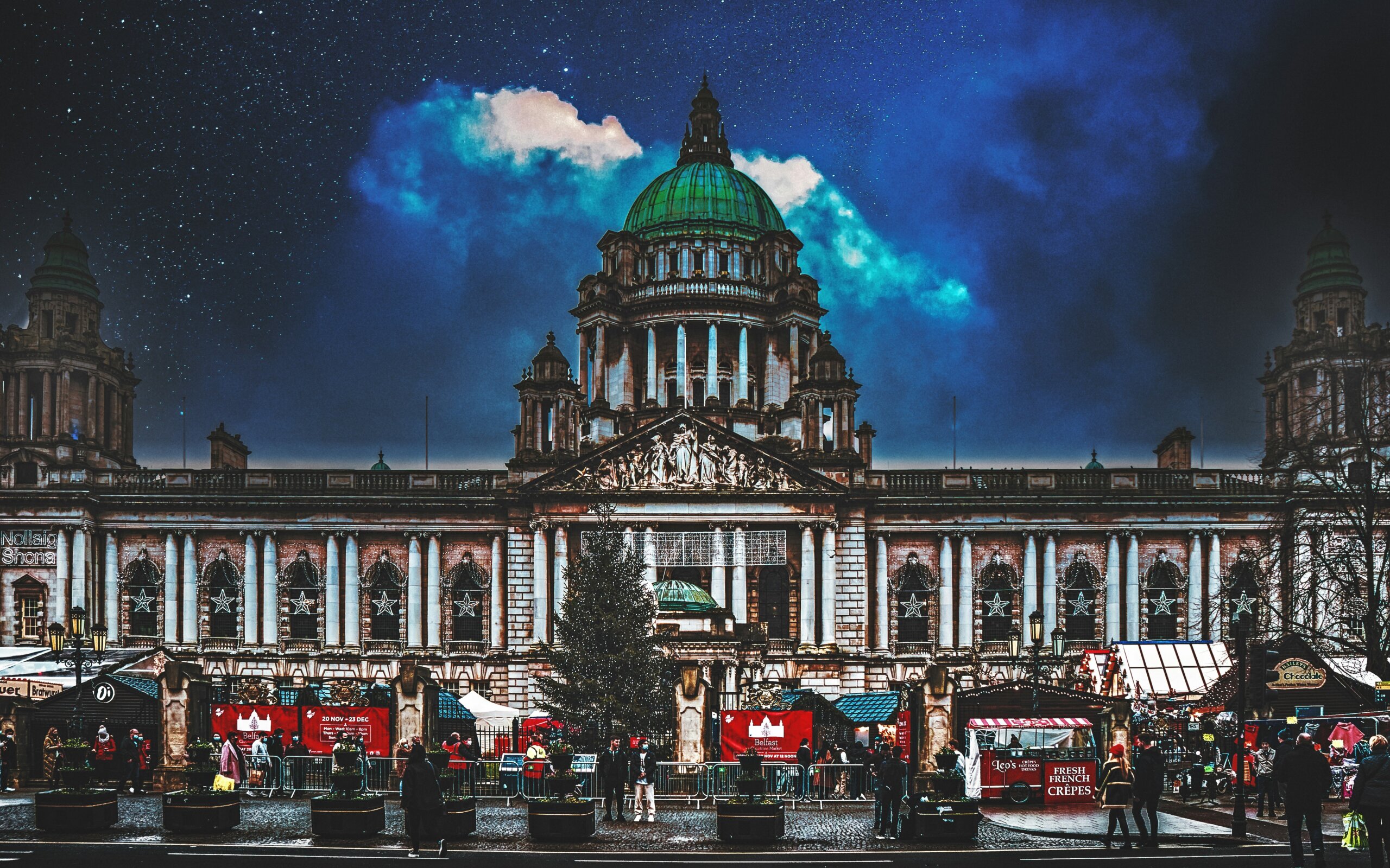 Belfast City Hall Christmas Market at night with festive lights and holiday stalls in Ireland