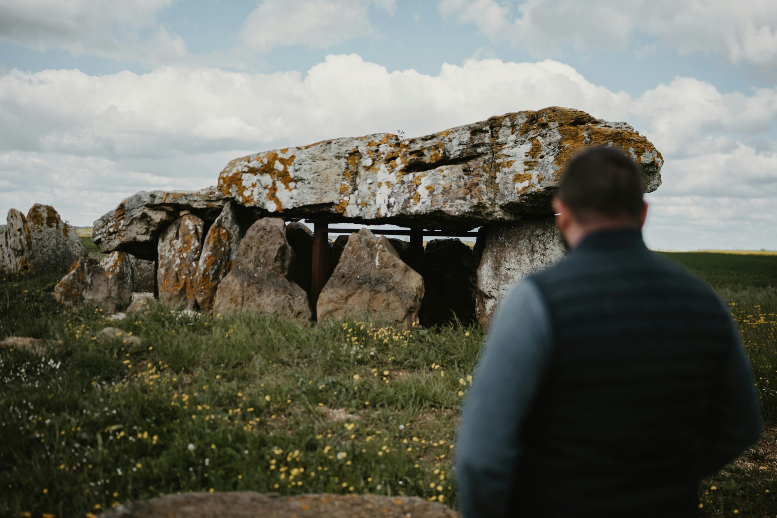 Stone dolmen in Ireland’s Ancient East with a visitor standing nearby under cloudy skies