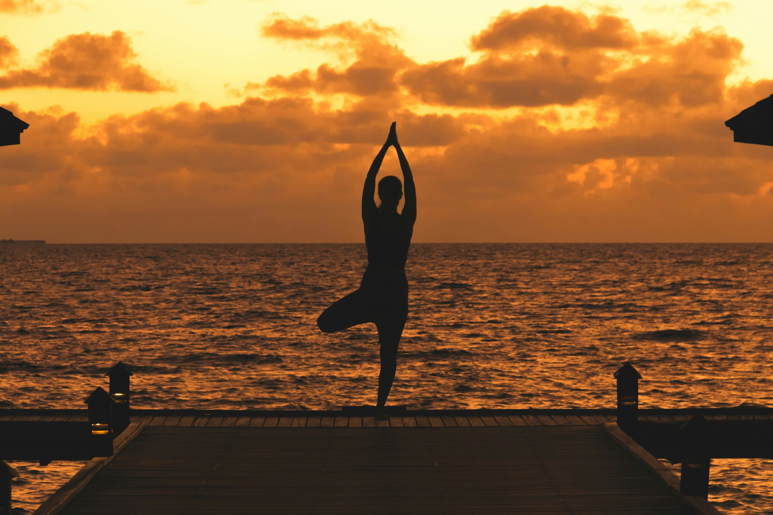 Woman doing sunrise yoga on an ocean deck during a wellness retreat
