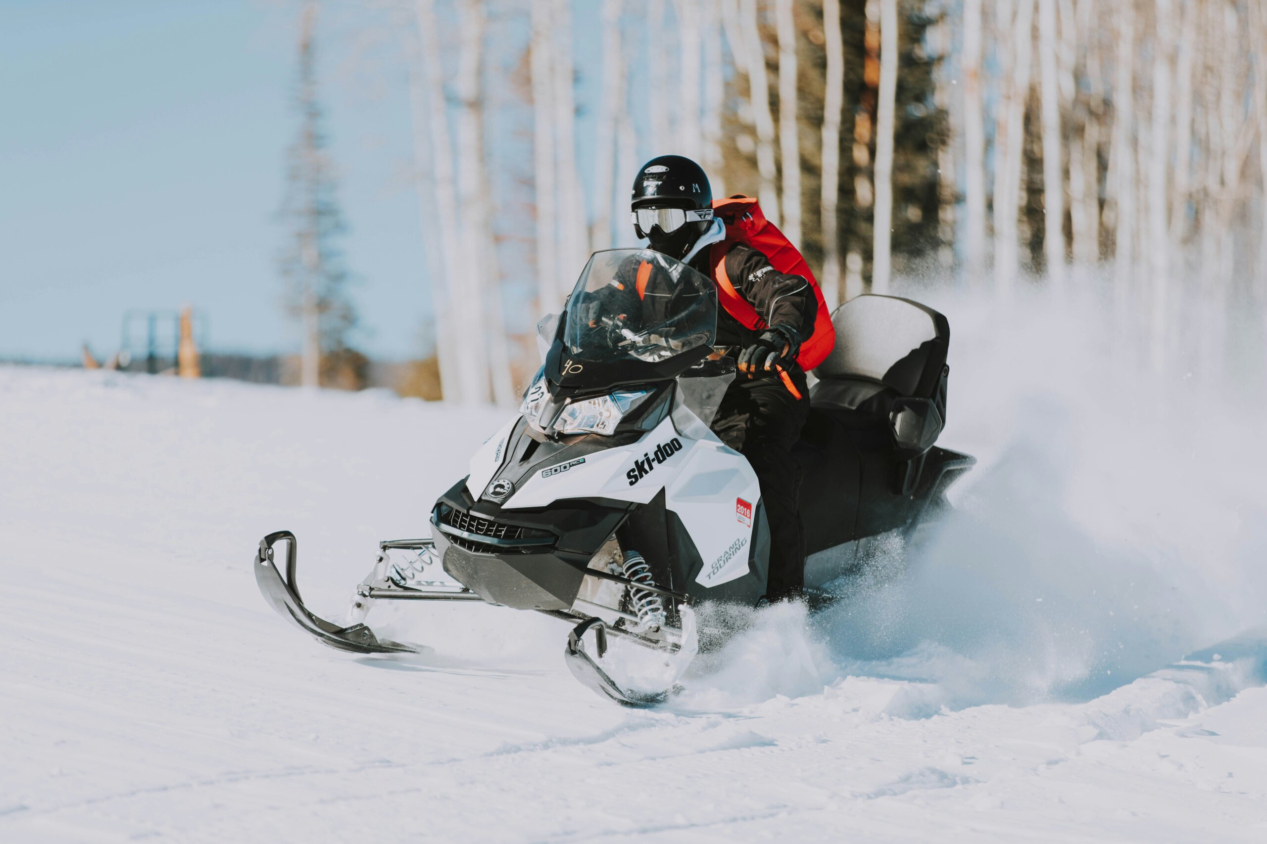 Snowmobiler riding through fresh snow in winter forest, symbolizing thrilling snowmobiling adventures and travel destinations.