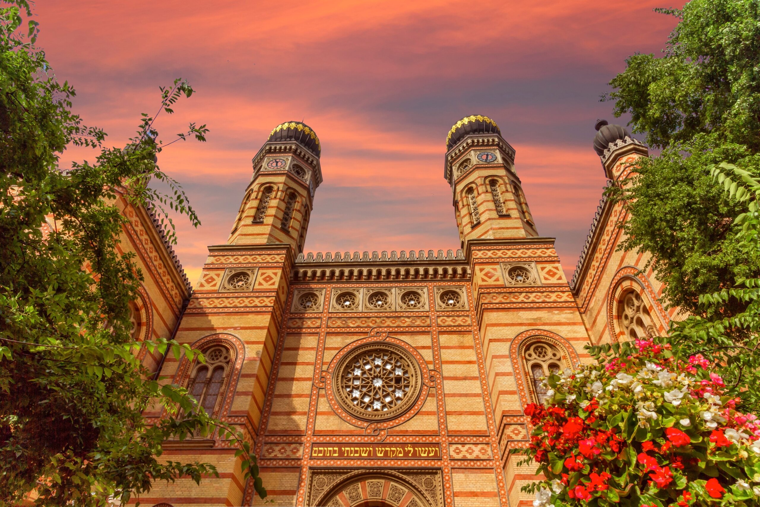 Historic synagogue with ornate domes and detailed façade at sunset.