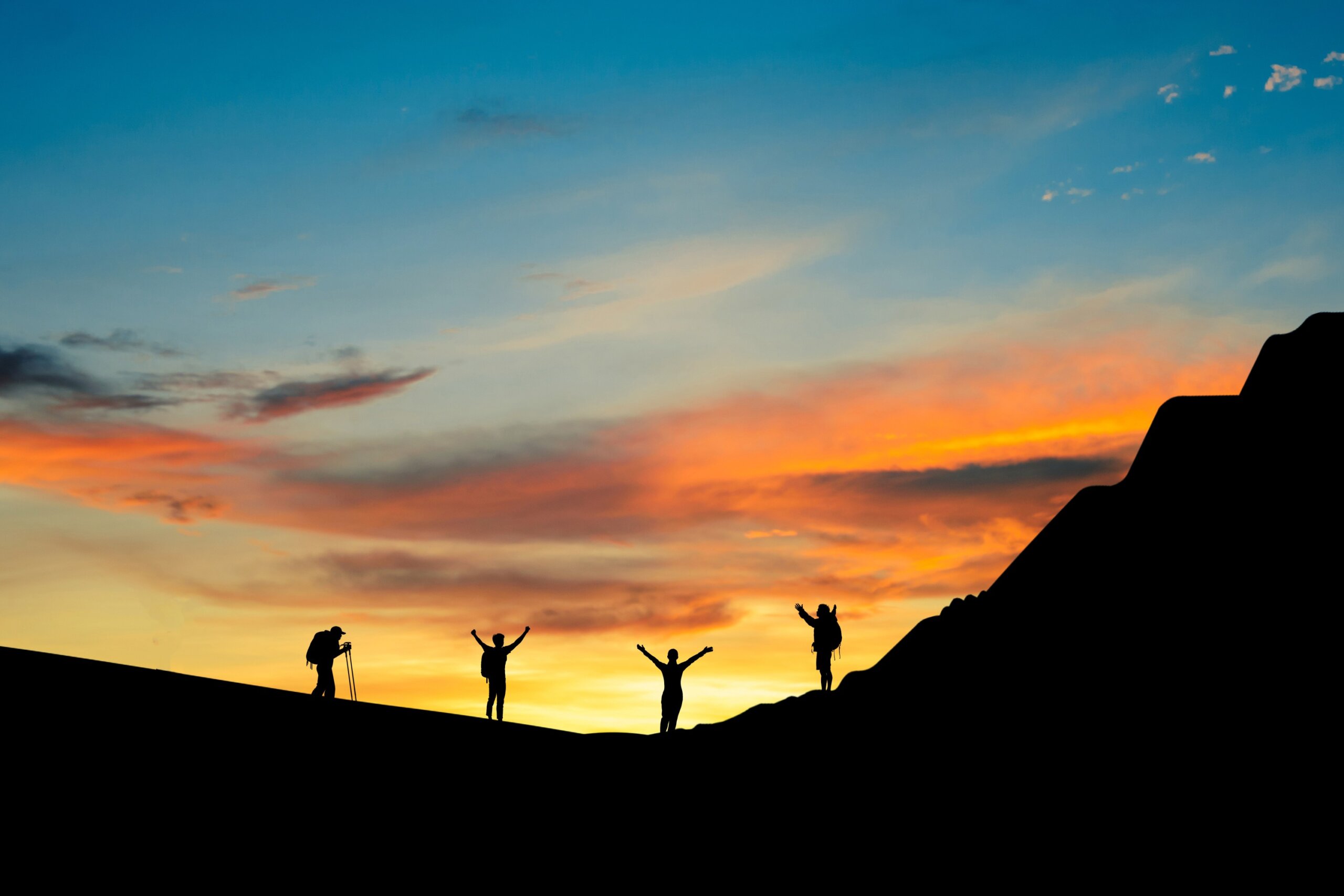 Small group of hikers silhouetted against a colorful sunset sky