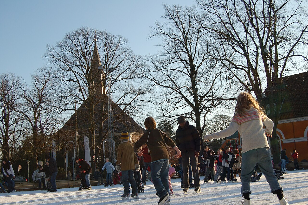 Ice-skaters on the out-door ice-skating rink at Frederiksberg Runddel in the Frederiksberg district of Copenhagen, Denmark, with Frederiksberg Church as a backdrop